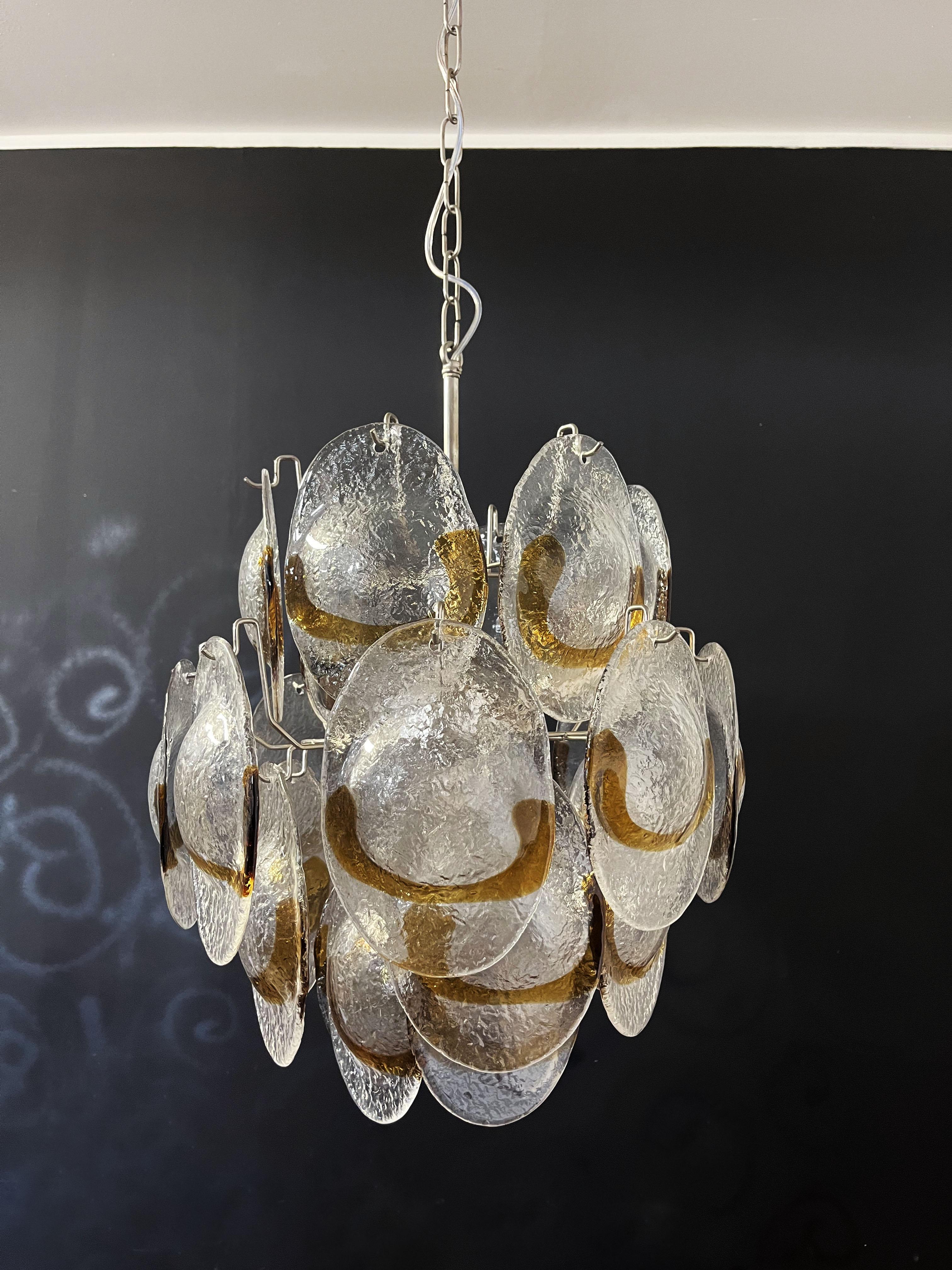 Vintage Italian Murano chandelier in Vistosi style. The chandelier has 24 glasses in a nickel metal frame. The originality of this chandelier is given by the glass, wonderful works of art trasparent and amber, called shells. Murano blown glass in a