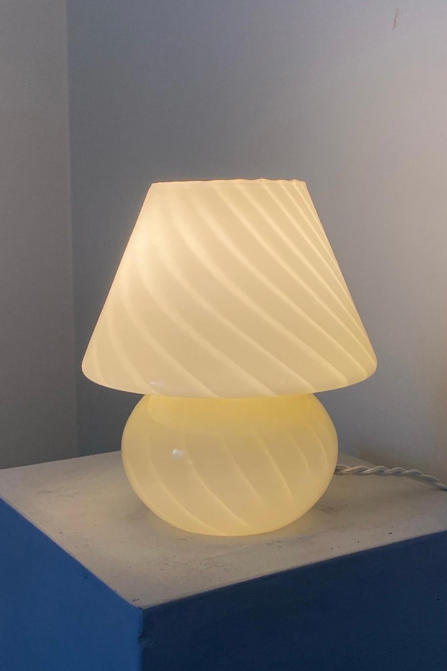 Beautiful vintage Murano baby mushroom table lamp. Mouth blown in creamy yellow glass with swirl. The perfect size for a bedside table. Handmade in Italy, 1970s, and comes with twisted fabric cord. Measures: H: 20 cm, D: 16 cm.
 