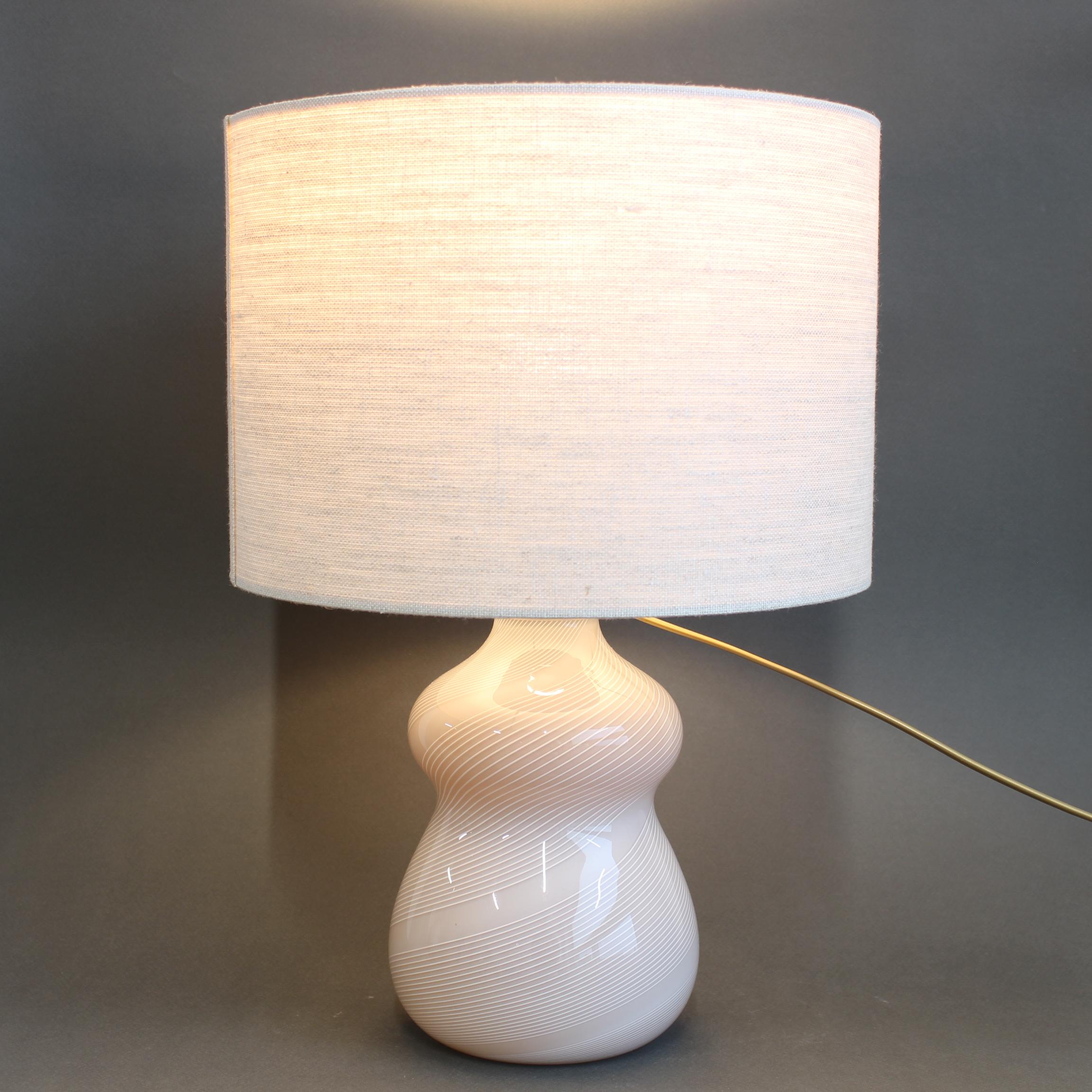 Tischlampe aus italienischem Murano-Glas (ca. 1970er Jahre). Ein lineares Design, das sich kreisförmig um den Lampensockel wickelt, sorgt für einen atemberaubenden Effekt, sowohl wenn die Lampe beleuchtet ist als auch wenn sie ausgeschaltet ist. Die