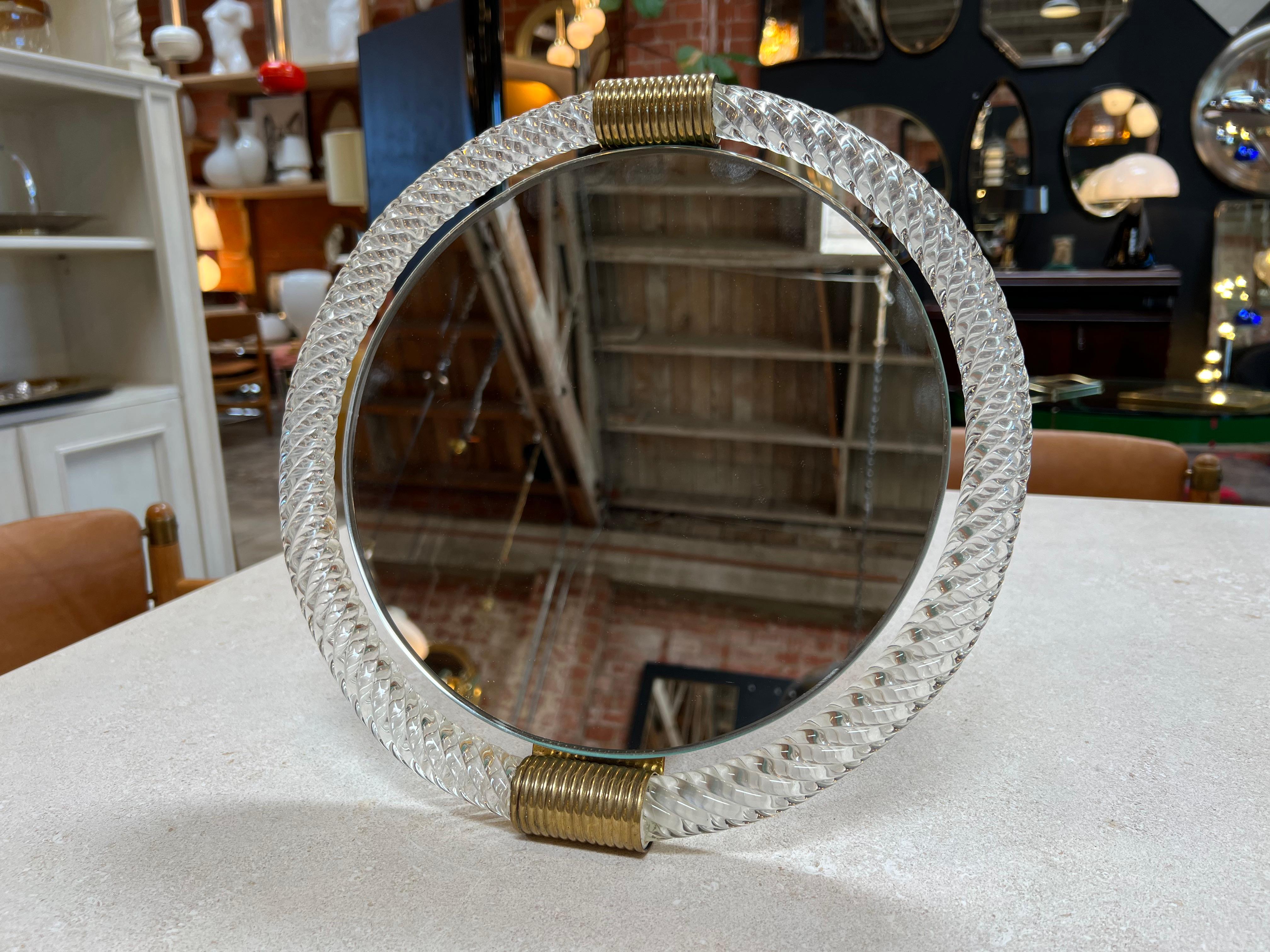 The Vintage Italian Murano Round Table Mirror from the 1960s is a captivating and reflective piece that embodies the renowned Murano glass craftsmanship. Made in Italy, this mirror features intricate designs within its round frame, showcasing the