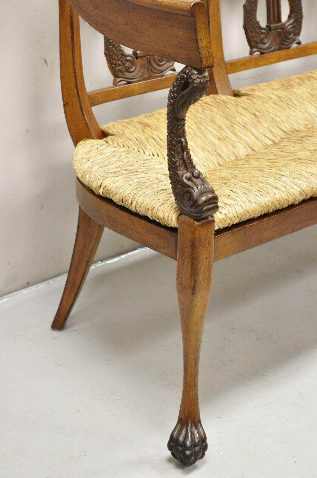 Vintage Italian Neoclassical Regency Style Serpent Lyre Carved Rush Seat Bench. Item featured has a solid carved wood frame, distressed finish, woven rope cord rush seat, serpent carved supports, carved paw feet, very nice item. Circa Late 20th
