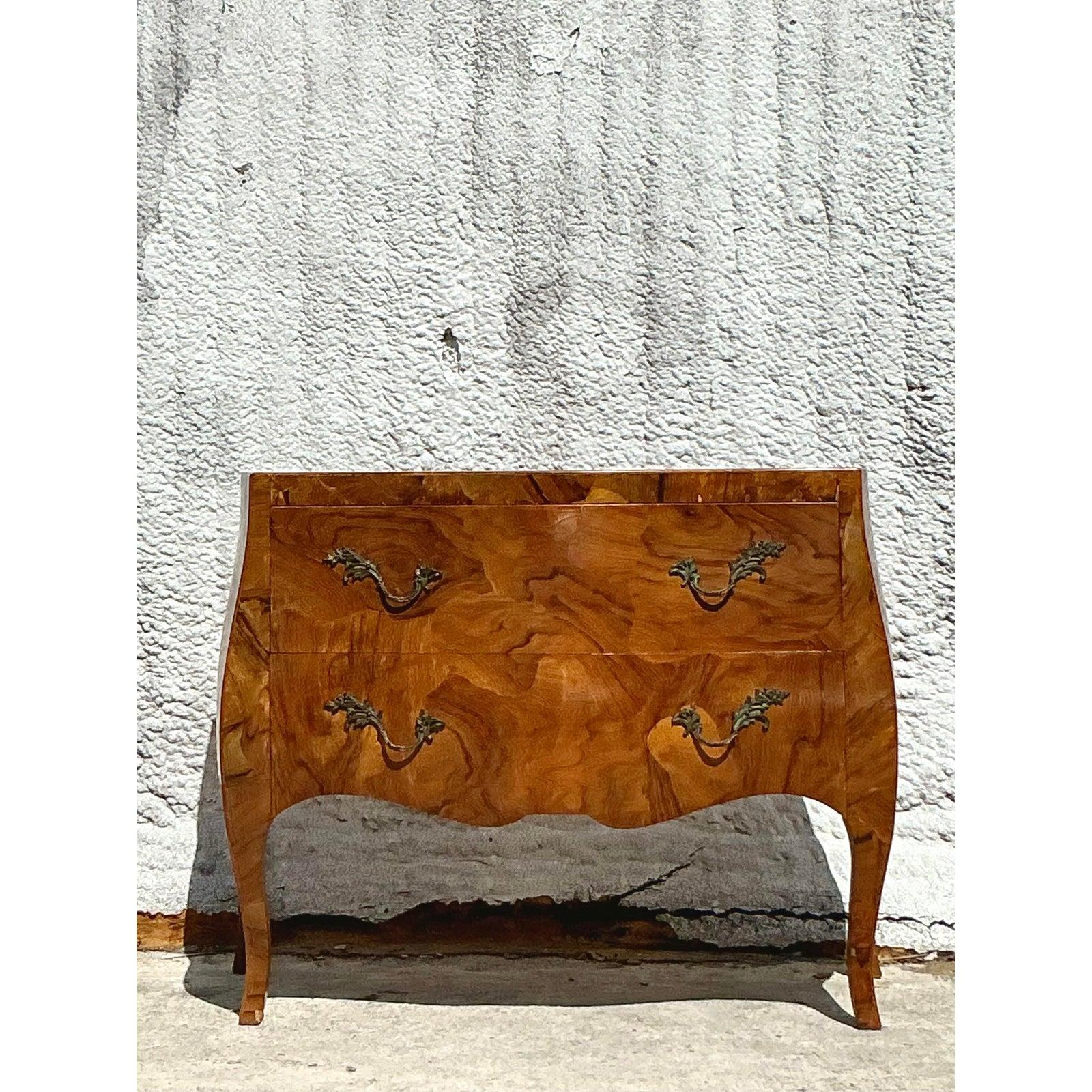 Elevate your interiors with the timeless elegance of this Vintage Italian Olive Burl Wood Bombe Chest. Crafted with exquisite attention to detail, this sophisticated piece features a beautifully figured olive burl veneer, rich in natural patterning