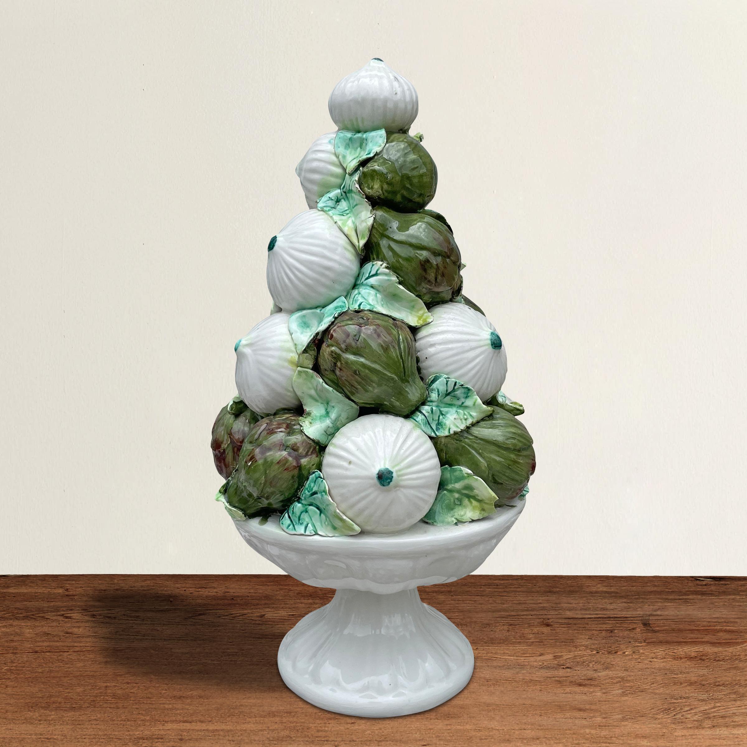 A charming vintage Italian porcelain sculpture depicting a stacked grouping of onions and artichokes and resting on a tazza-form base.