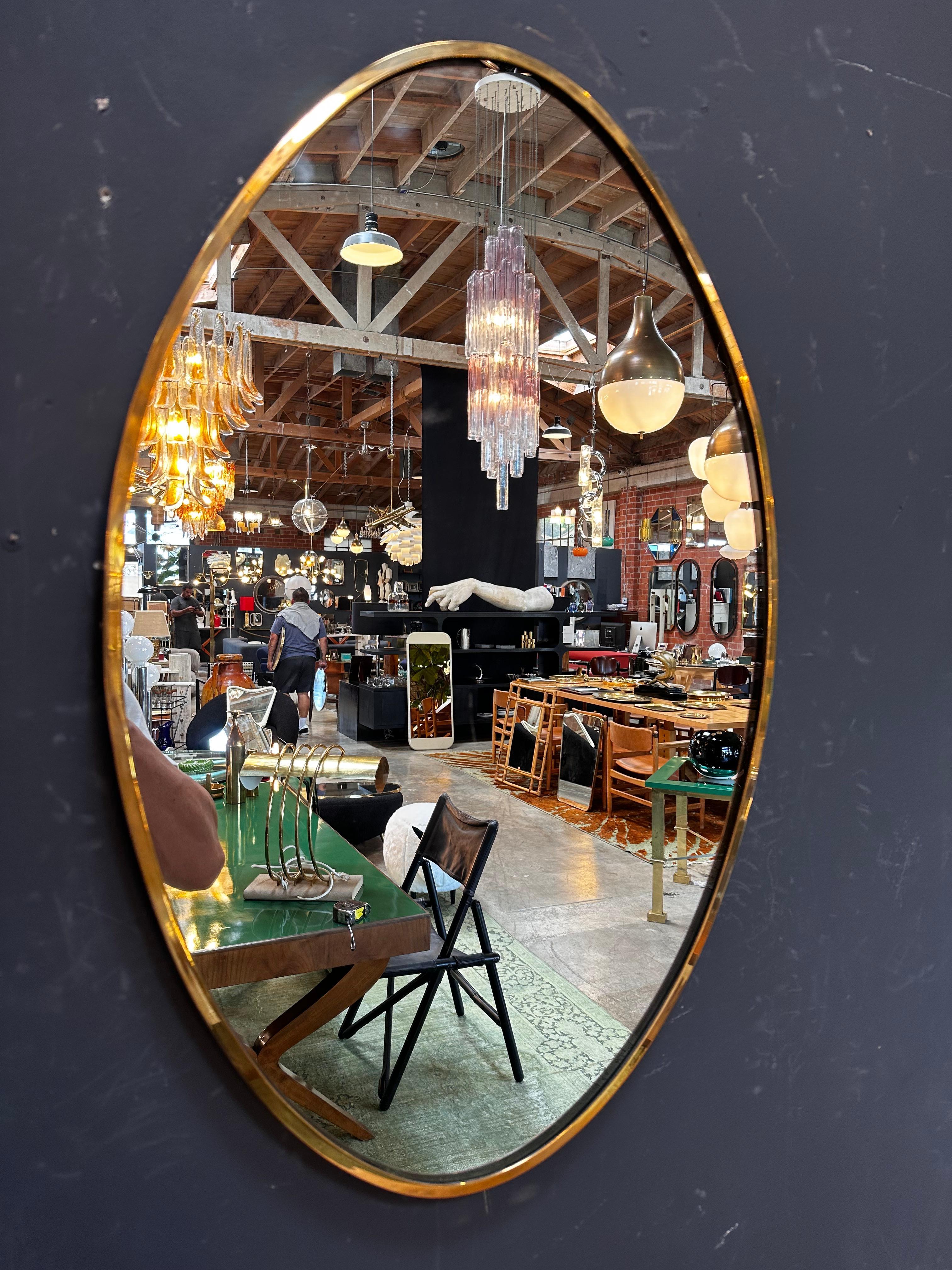 Der Vintage Italian Oval Brass Wall Mirror aus den 1980er Jahren ist ein klassisches und elegantes Stück mit einer zeitlosen ovalen Form und einem schönen Messingrahmen.

