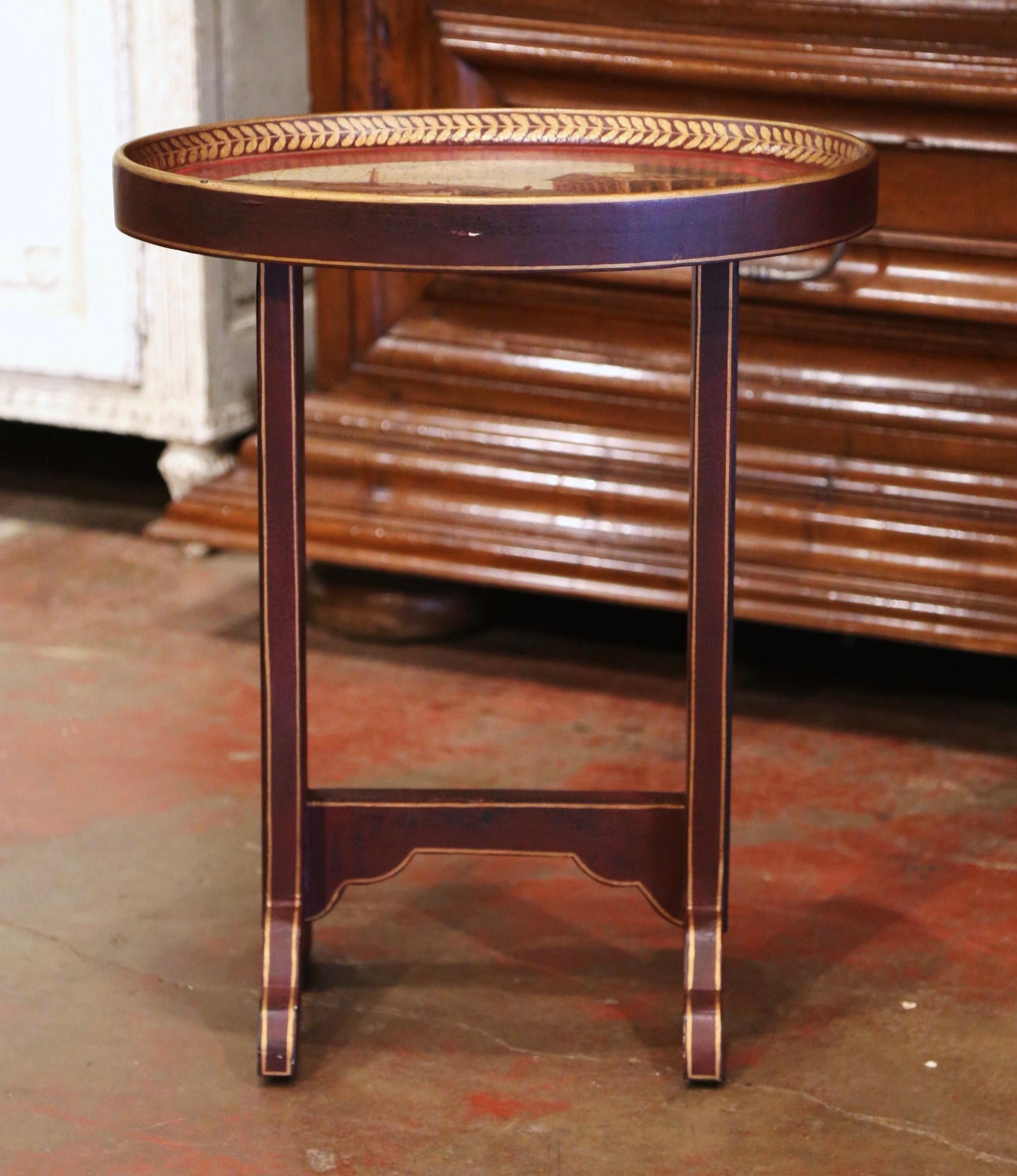 Place this elegant side table next to a chair of sofa. Crafted in Italy circa 2000, the small colorful occasional table stands on a trestle base connected with a stretcher at the base. The oval top with raised edges is decorated with an hand painted