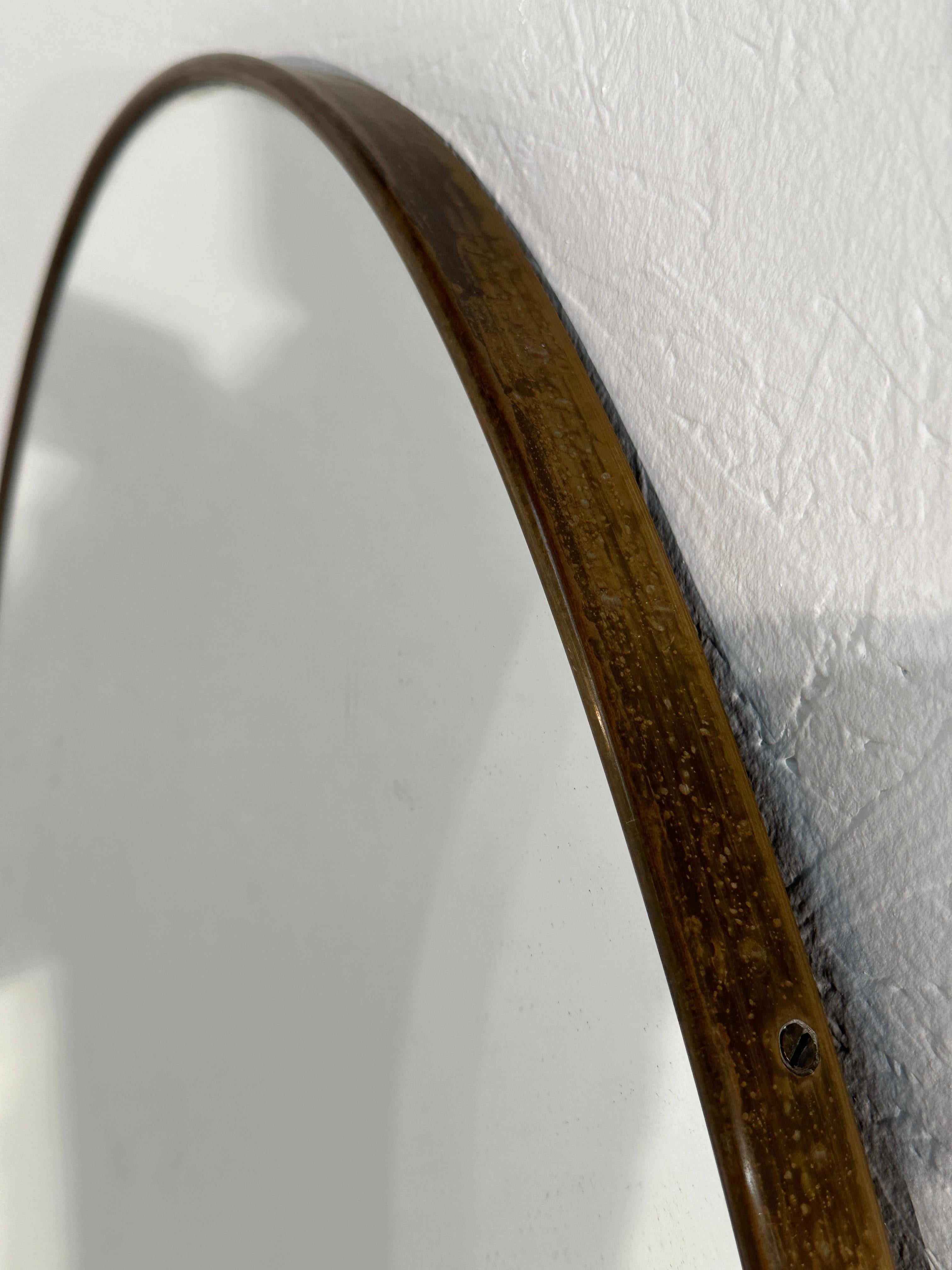 Der ovale italienische Vintage-Wandspiegel aus den 1960er Jahren ist ein Klassiker des Designs der Jahrhundertmitte. Der elegante, in Italien gefertigte Messingrahmen mit seiner ursprünglichen Patina verleiht ihm Charakter und Charme. Die ovale Form