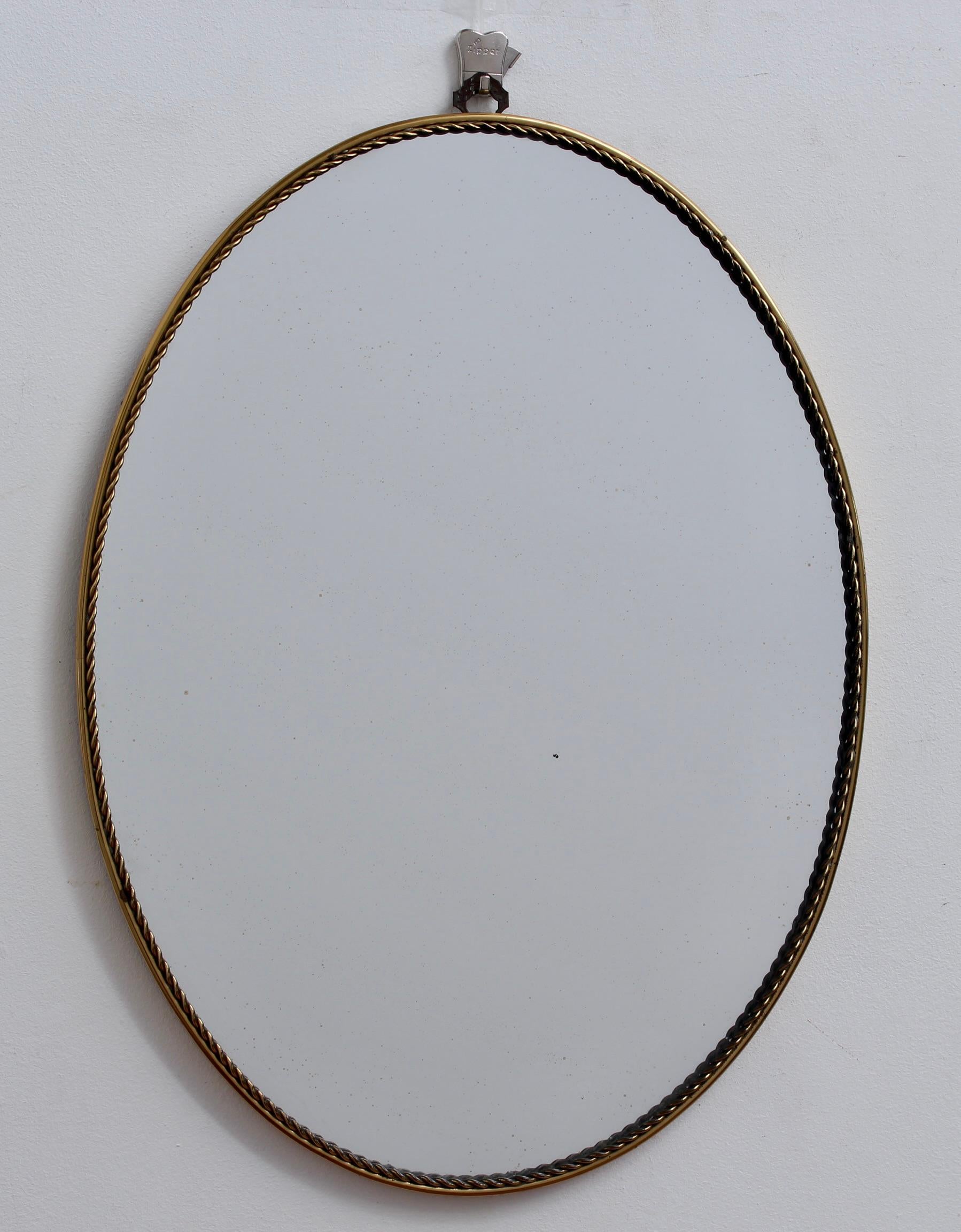 Small vintage Italian wall mirror in brass frame with stranded rope pattern (circa 1950s). The mirror has presence with a classic form and elegant good looks. The oval shape coupled with the frame's stranded rope pattern is a real find on the