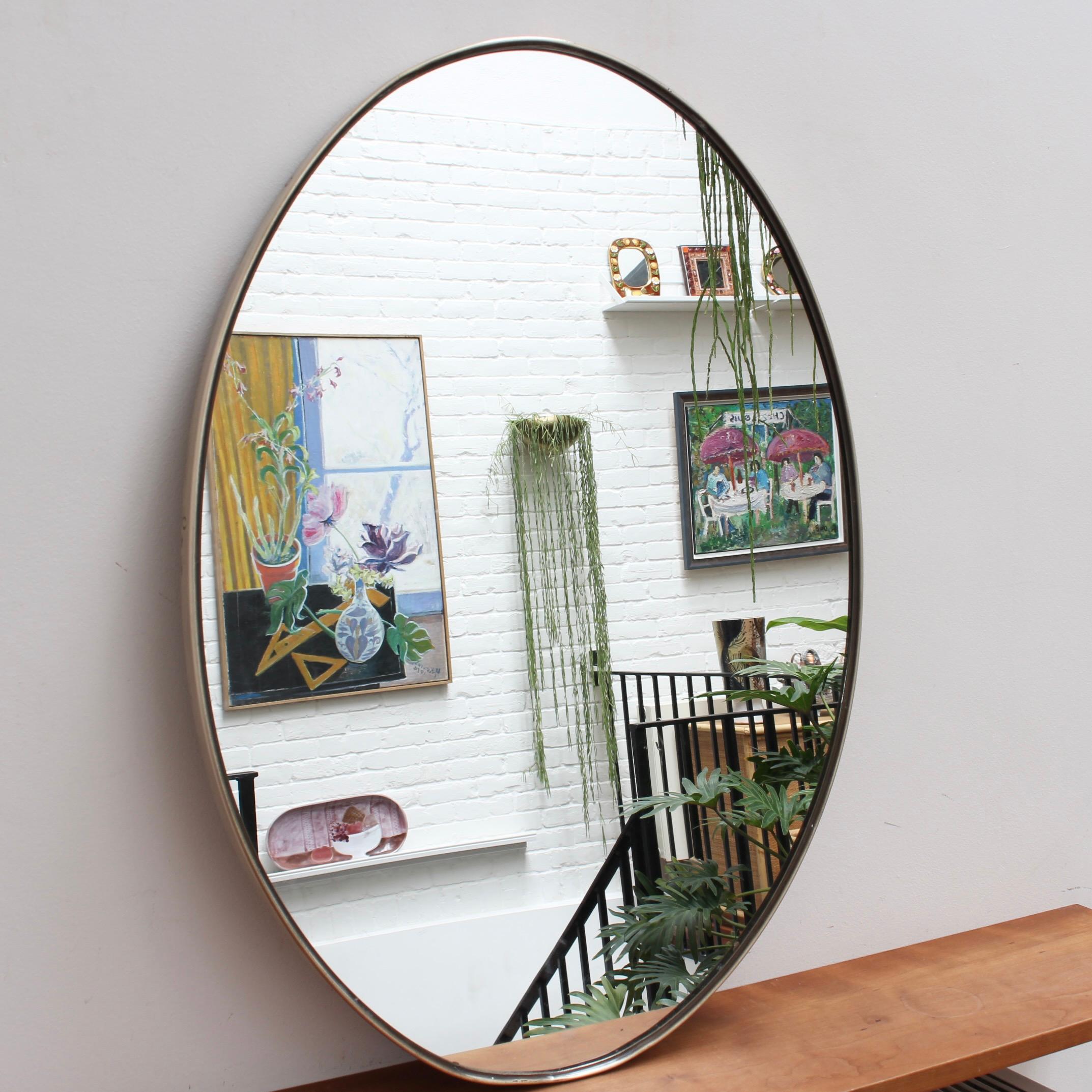 Mid-century Italian wall mirror with brass frame, circa 1950s. The mirror is oval in shape and very smart with rugged durability. The visual impression is elegant and very distinctive in a modern Gio Ponti style. In overall good condition with minor