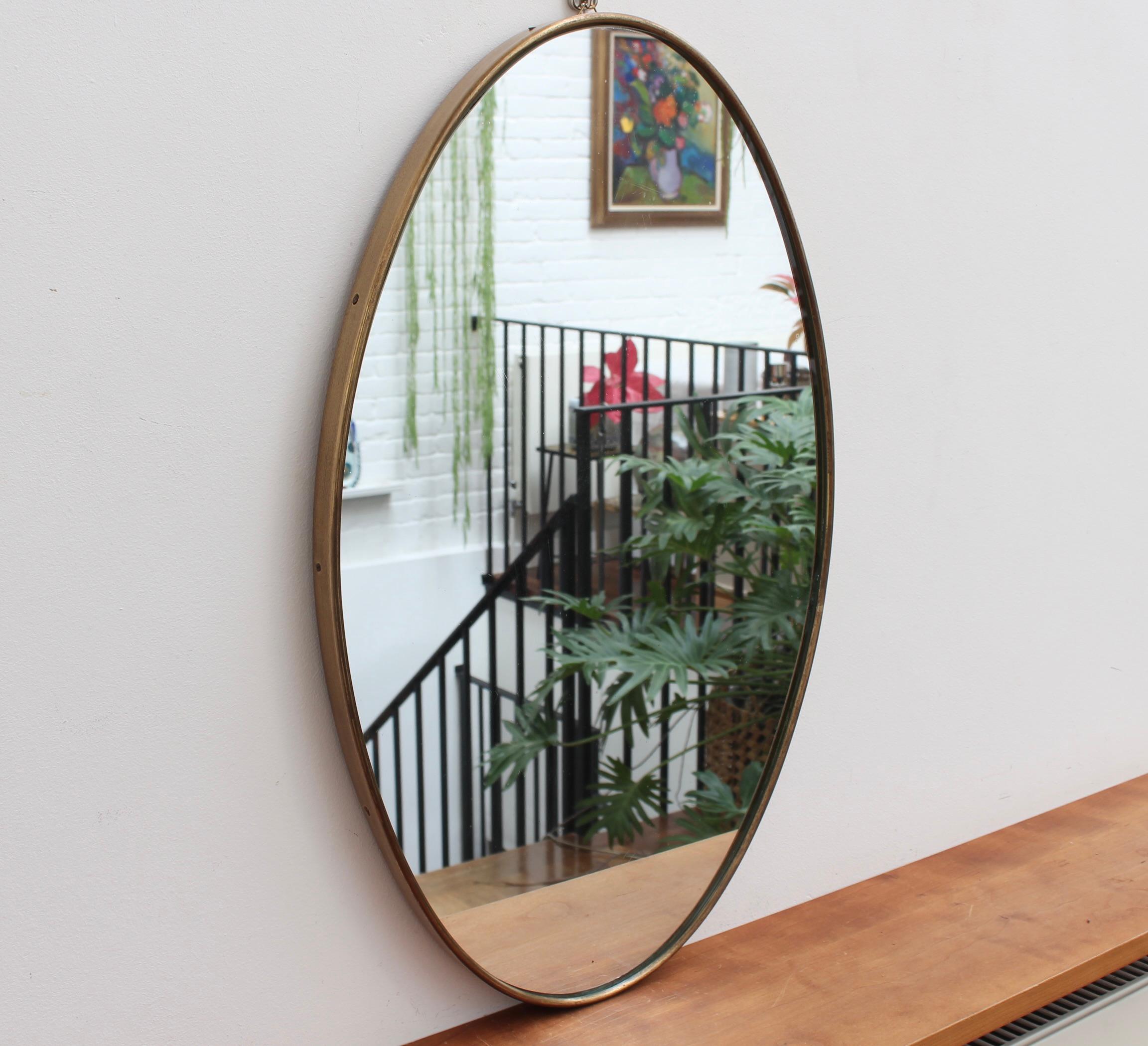 Mid-century Italian wall mirror with brass frame (circa 1950s). The mirror is oval in shape and very smart, with irresistible durability. The visual impression is elegant and very distinctive in a modern Gio Ponti style. The mirror is in overall