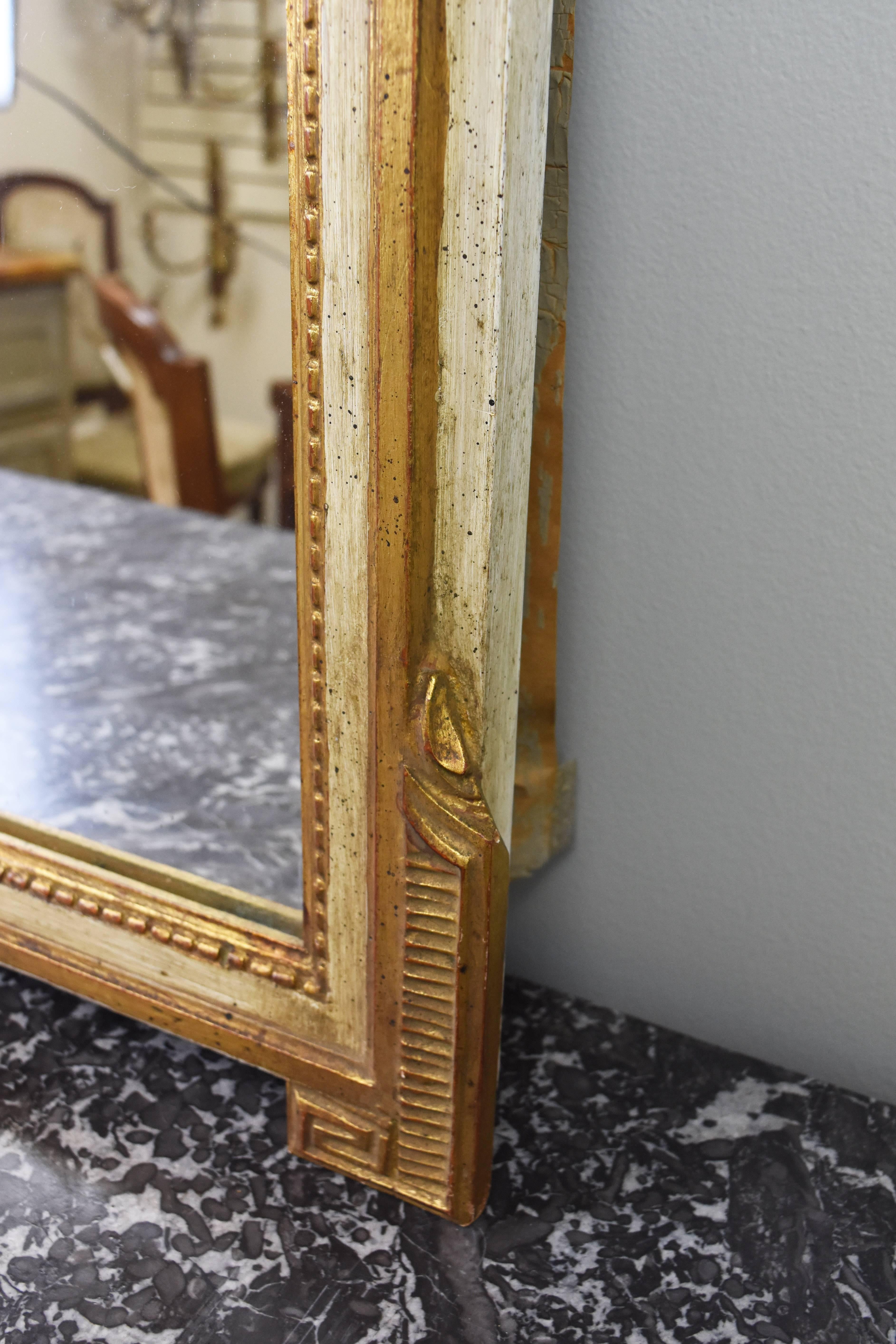 This vintage Italian mirror is decorated with scrolling acanthus leaves, beading and a Greek key design on the bottom frame corners, the finish is a lovely cream color with giltwood accents.