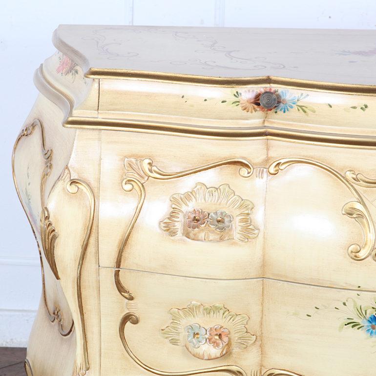 Vintage Italian ‘Rococo’ painted and carved bombe commode with gilt details and hand painted flower accents. Two small drawers above two large deeper drawers.