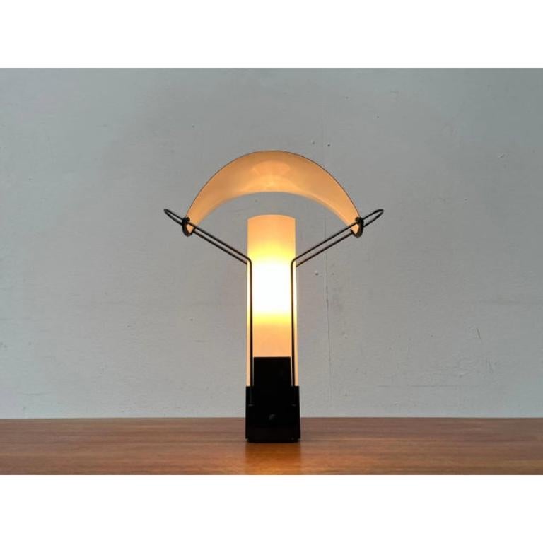 Rare table lamp from the Italian manufacturer Arteluce.

A draft in postmodern formal language. Filigree hangers wear a finely designed metal reflector sail with chrome -colored top. Everything is fixed in a heavy black base. The diffuser consists