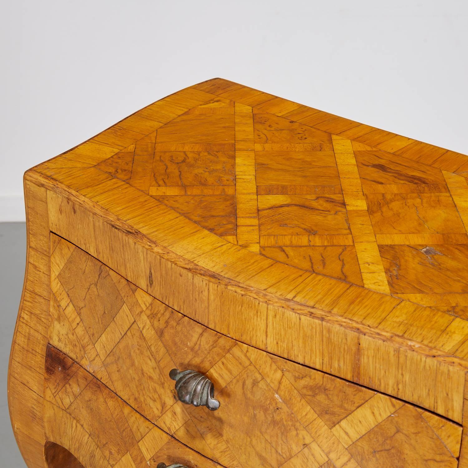 Mini commode a due cassetti in parquet italiano d'epoca, anni '40 circa. Una forma a serpentina realizzata in legno d'ulivo con intarsi a reticolo e disegno geometrico in parquet. La commode presenta due cassetti, gambe cabriole e tiretti a forma di