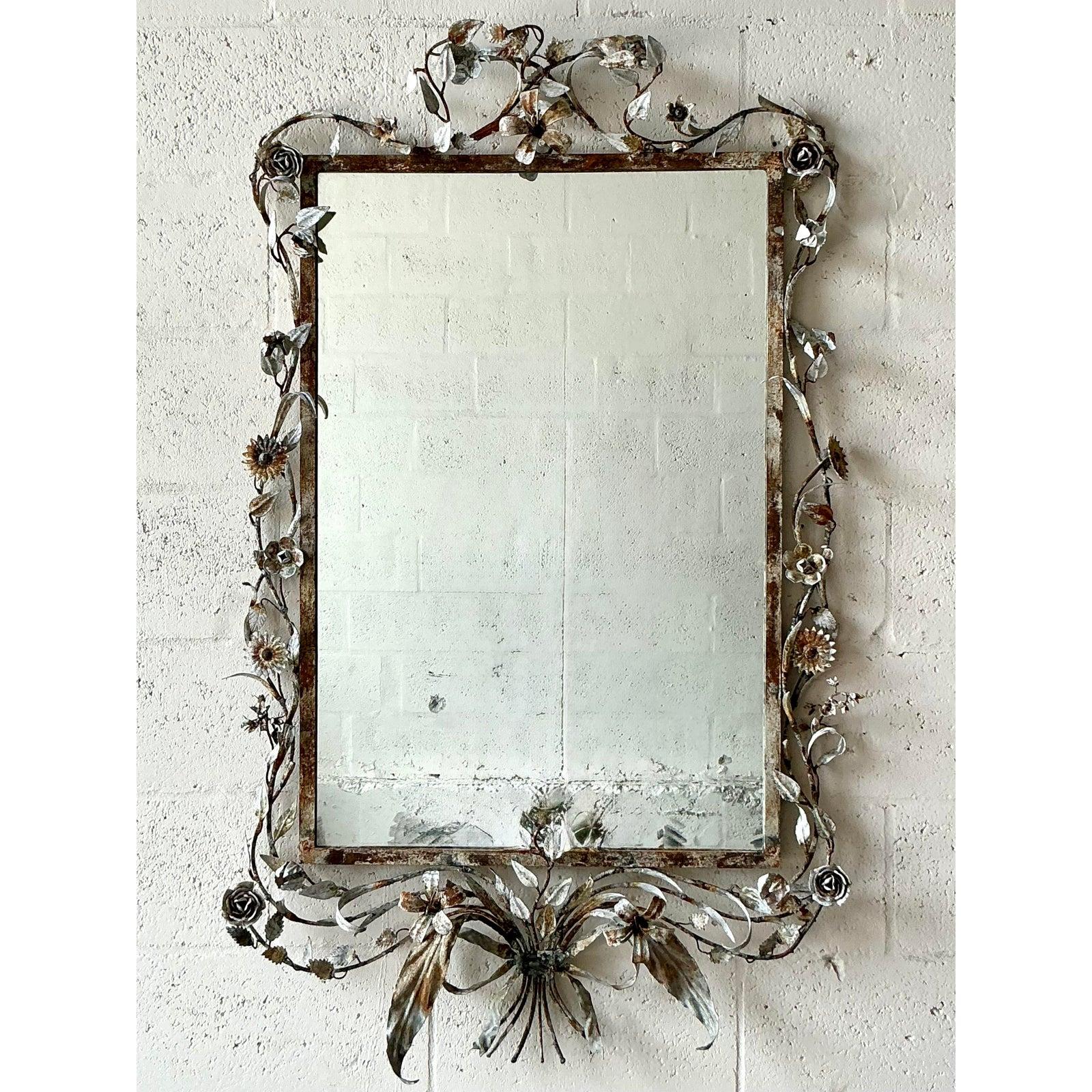 Esempio straordinario di arte italiana, questo specchio toleware vintage è un'accattivante danza di delicata metalleria e fascino romantico. L'intricata cornice forgiata a mano, ornata da un fiorente motivo di foglie e fiori, porta in casa tua il