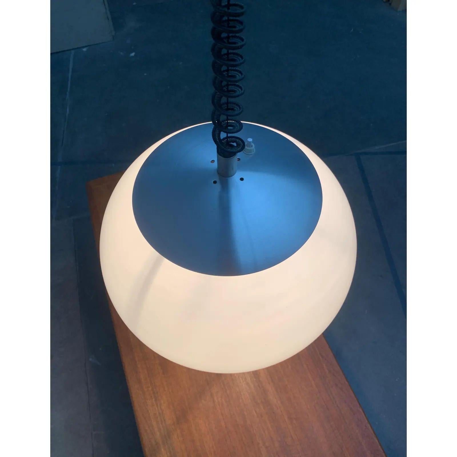 Lampada a sospensione italiana di Stilux Milano.

Il paralume della lampada è realizzato in plastica traslucida bianca. Nella parte superiore la lampada si chiude con un cappuccio in alluminio, nella parte inferiore con un ampio bordo in alluminio.