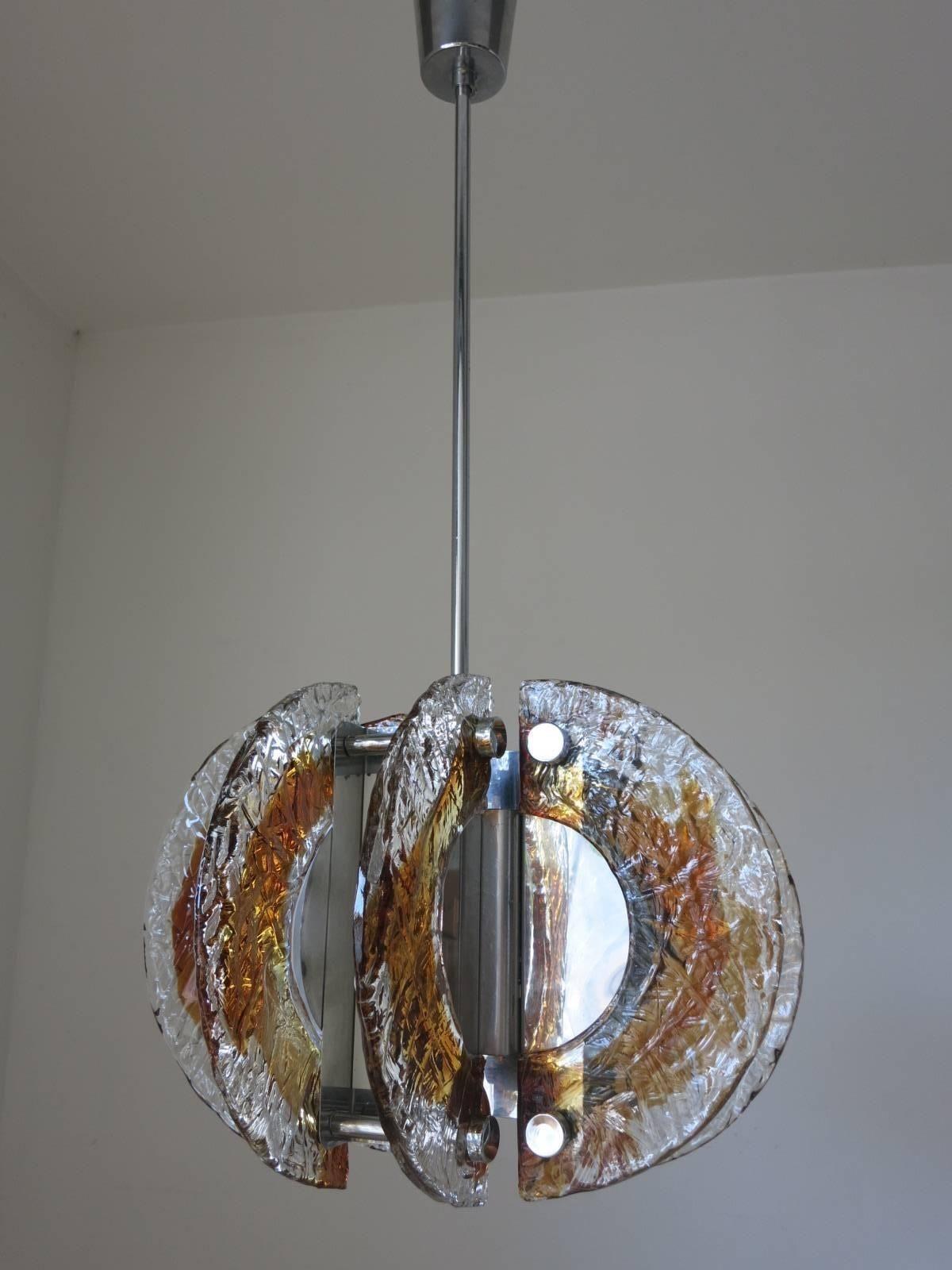 Vintage Italian pendant with clear and amber Murano glasses hand blown into half moon shapes, mounted on chrome frame. Designed by Mazzega, Italy, circa 1960s. 
Dimensions (including rod & canopy)
36