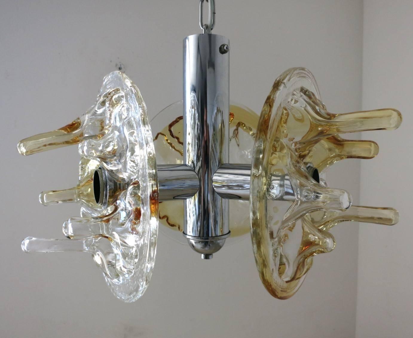 This abstract vintage Italian pendant made in the 1960's by Mazzega features a blend of clear and amber handblown Murano glass with a unique abstract shape. The Murano glass disks are carefully mounted on a chrome frame. The light fixture is rewired