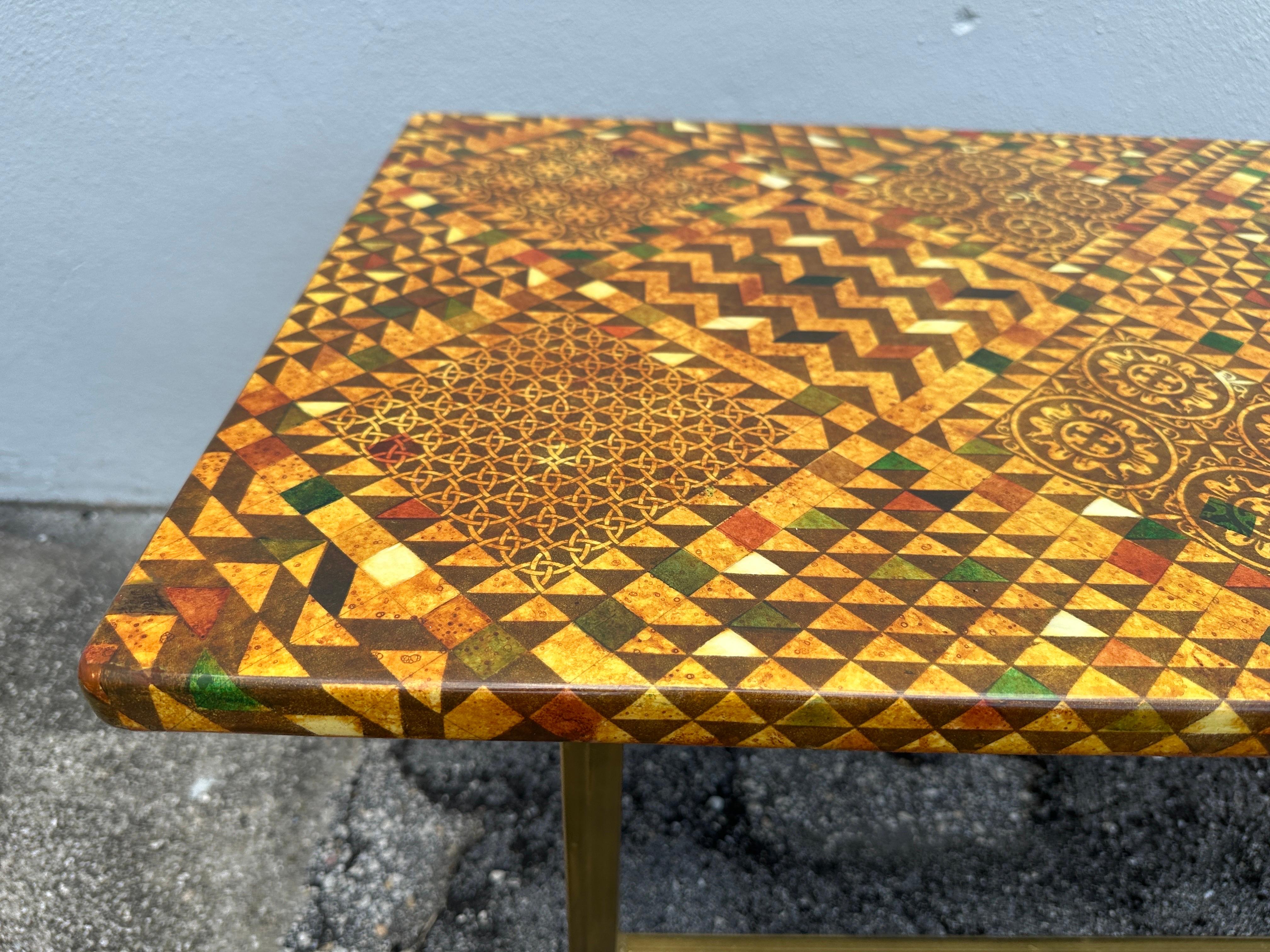 This vintage Piero Fornasetti coffee table, Milano, Italy. Graphic patchwork design with triangles and chevrons - lithographic transfer on wood. Brass finish patinated metal base. Labelled to underside.  THIS ITEM IS LOCATED AND WILL SHIP FROM OUR