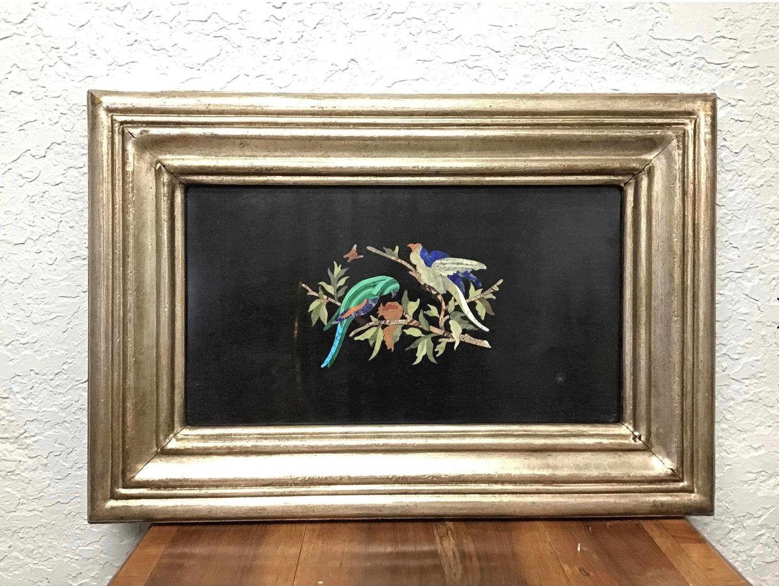 bItalian Pietra Dura bird plaque. Depicts colorful bird made of precious stone inlaid on black marble, standing on a branch having flowers and leaves, also precious stone. Above are butterfly in flight. The silver gilded frame is original to the