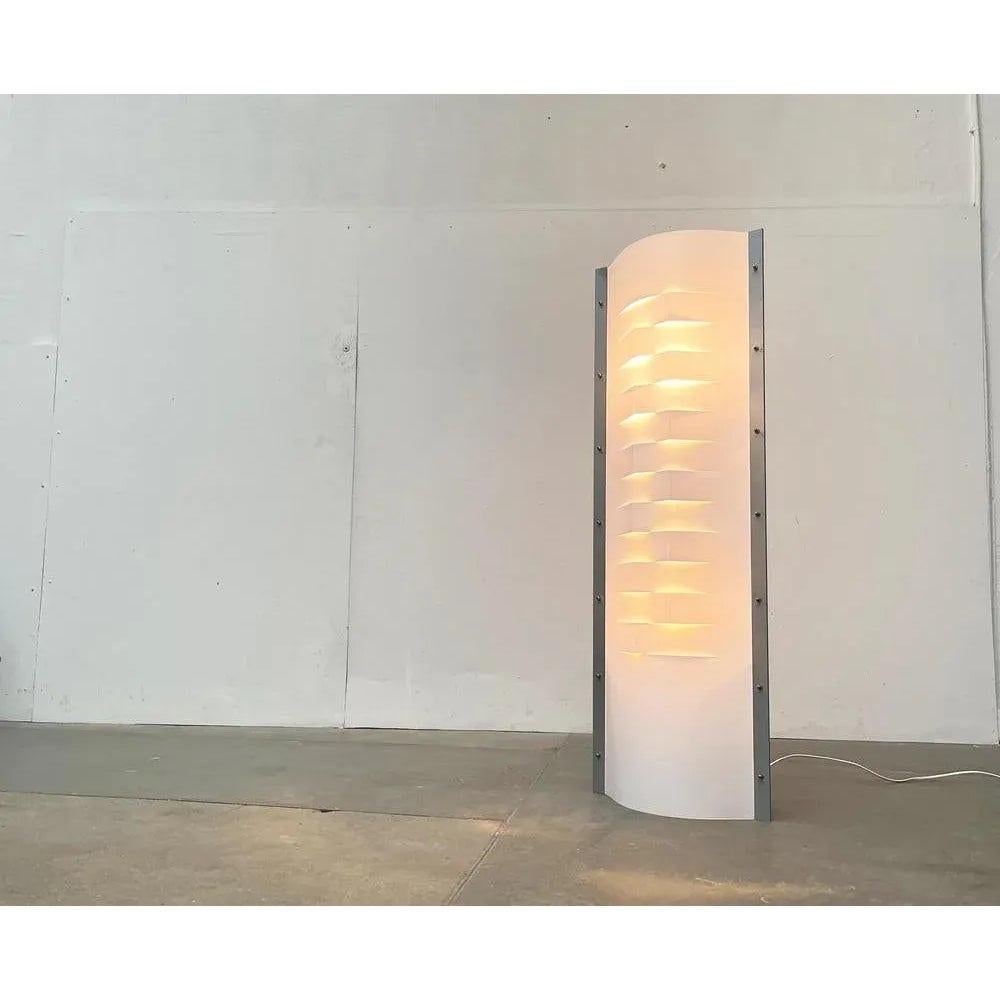 Lampadaire postmoderne du fabricant italien Slamp des années 90.

Le corps du luminaire sert de diffuseur et se compose de plastique translucide opalflex. La lampe comporte deux surfaces en plastique qui sont serrées et pliées en forme de lentilles.