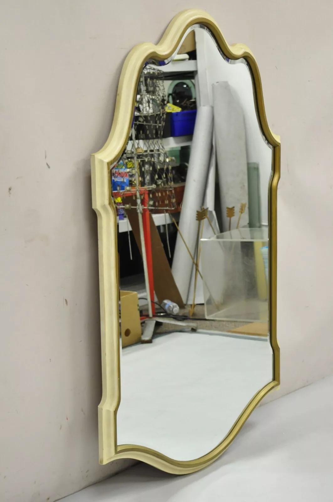 Specchio da parete con cornice smerlata color crema e oro con vetro smussato, Vintage Italian Glass Hollywood Regency. L'articolo è caratterizzato da una struttura in resina modellata, finitura verniciata color crema con finiture in oro brunito,