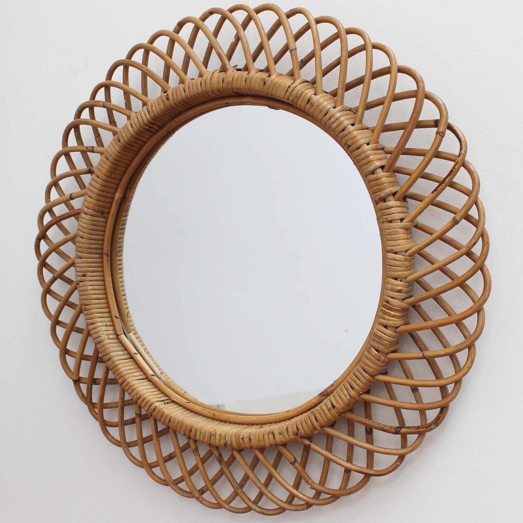Italian rattan round wall mirror (circa 1960s) in the style of Franco Albini. This is a mirror with substantial depth and a complex weave of rattan. There is a beautiful patina on the rattan and it is in good vintage condition. The original mirror