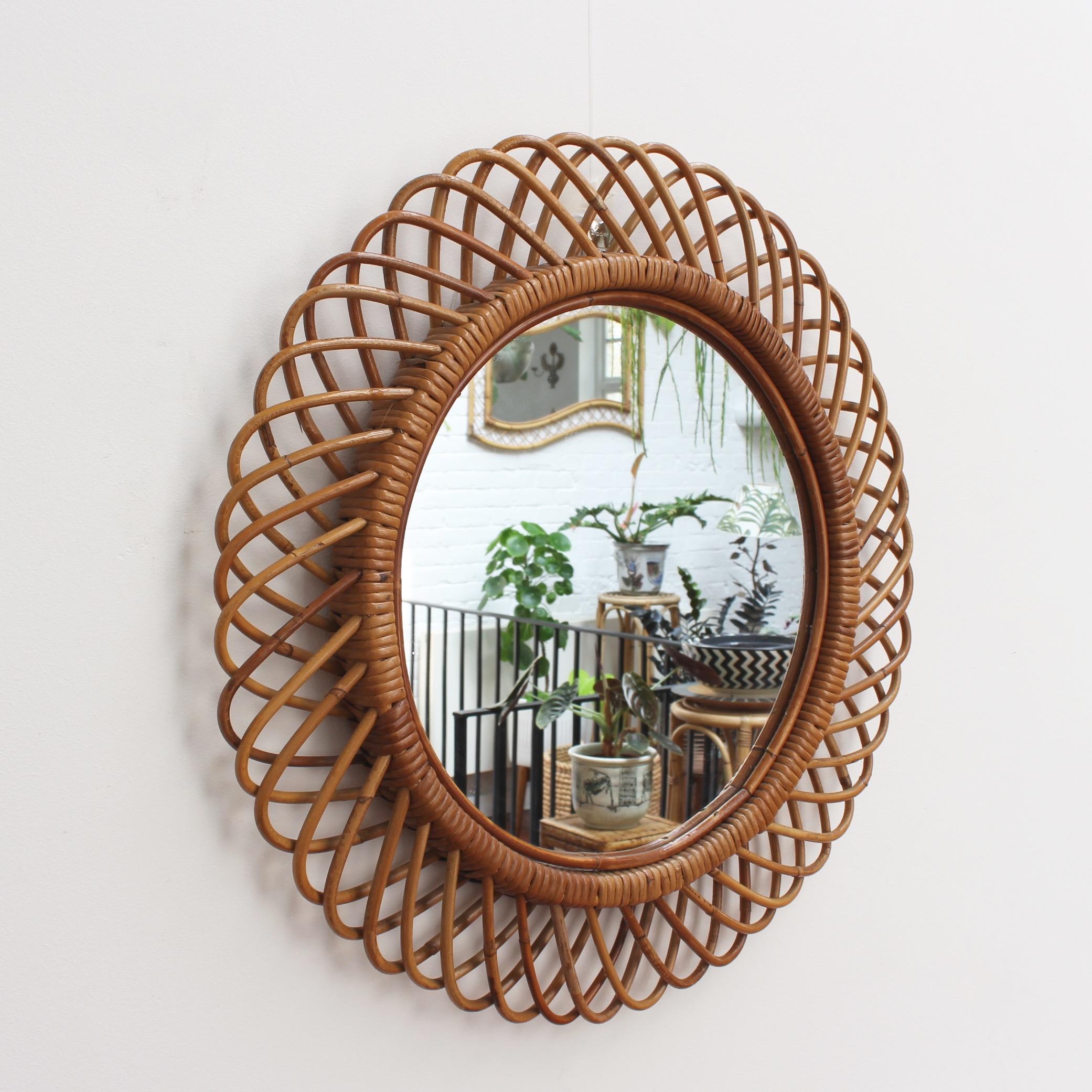 Italian rattan round wall mirror (circa 1960s) in the style of Franco Albini. This is a mirror with substantial depth and a complex weave of rattan. There is a beautiful patina on the rattan and it is in good vintage condition consistent with its