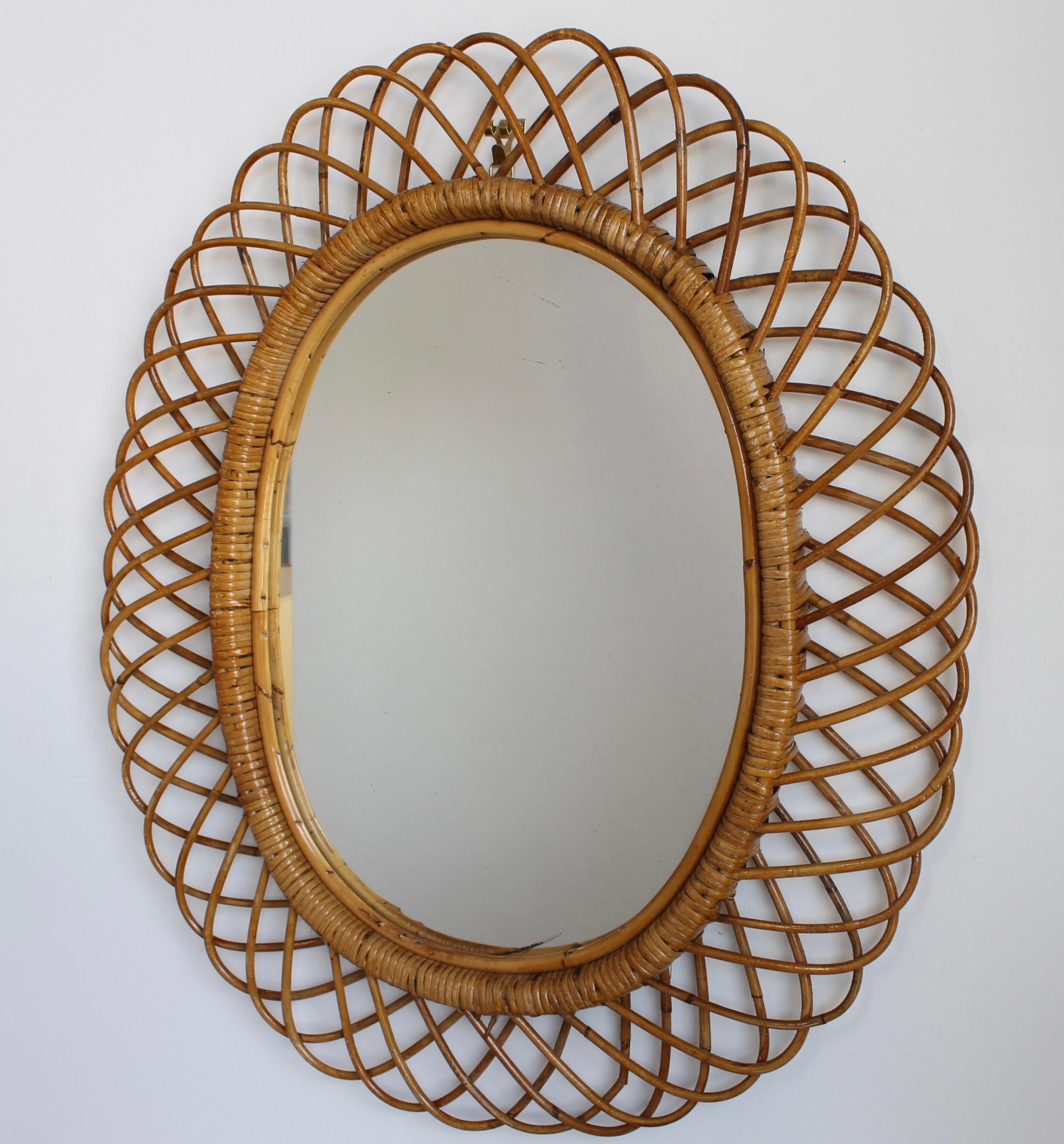 Wandspiegel aus Rattan (ca. 1960er Jahre) in dem unnachahmlichen italienischen Stil, der so beliebt ist. Dieser Spiegel hat ein komplexes Rattan-Geflecht, das sich in einer Reihe von hufeisenförmigen Vorsprüngen am Rand des Rahmens fortsetzt. Es