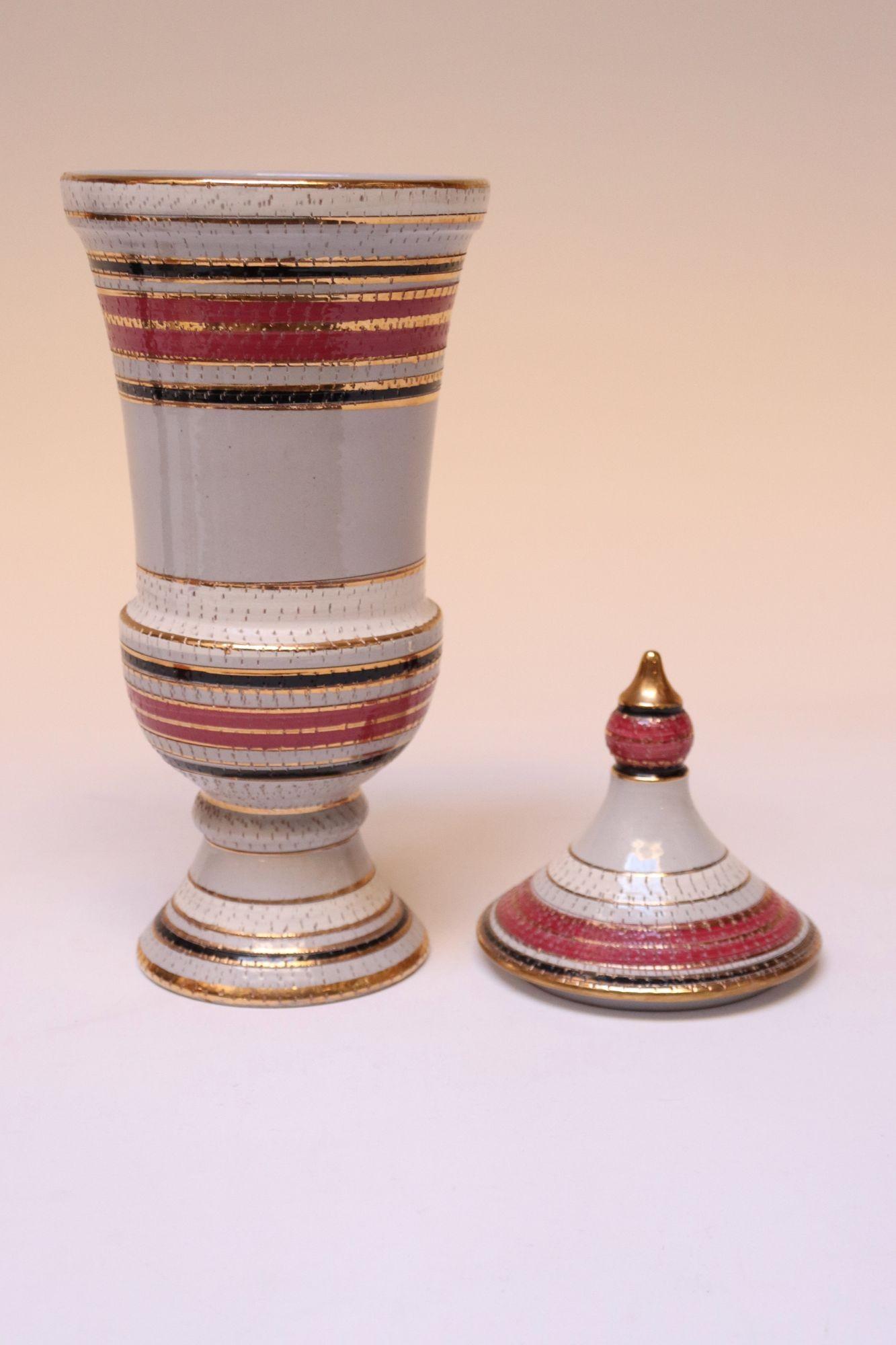 Italian Mid-Century Modernist Raymor ceramic lidded jar/urn (ca. 1950s, Italy). Attributed to Aldo Londi/Bitossi, though unconfirmed.
Pinprick incisions throughout amid banded motifs in pink, black, and gilt glaze.
Statuesque, impressive piece with