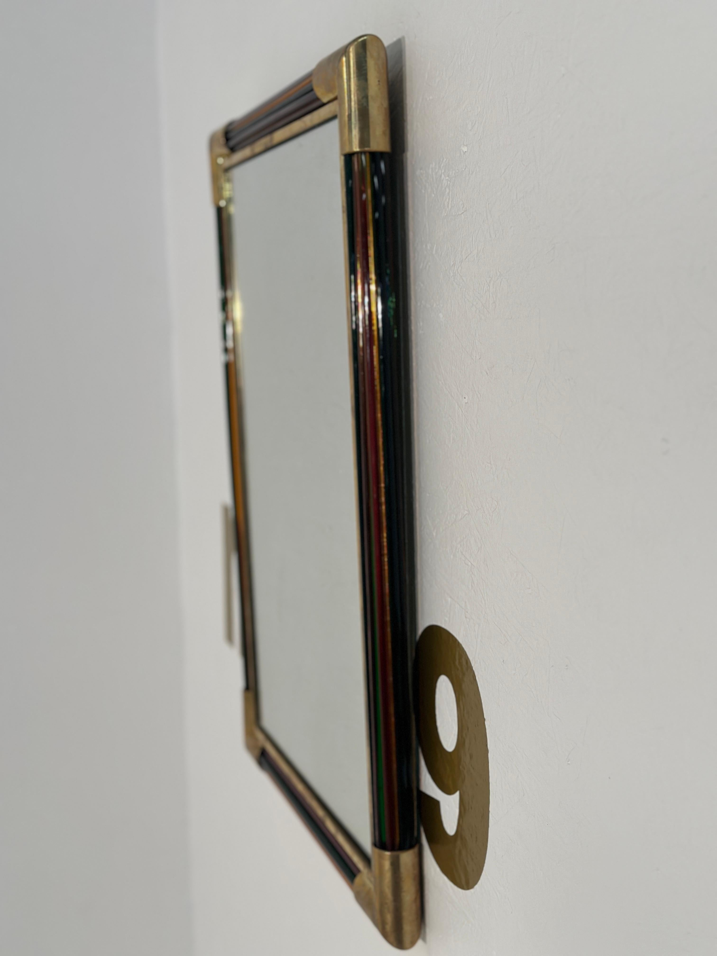 The Vintage Italian Rectangular Brass and Glass Wall Mirror from the 1980s features a distinctive design with brass corners and a round glass frame, exuding timeless elegance and Italian craftsmanship of the era.

