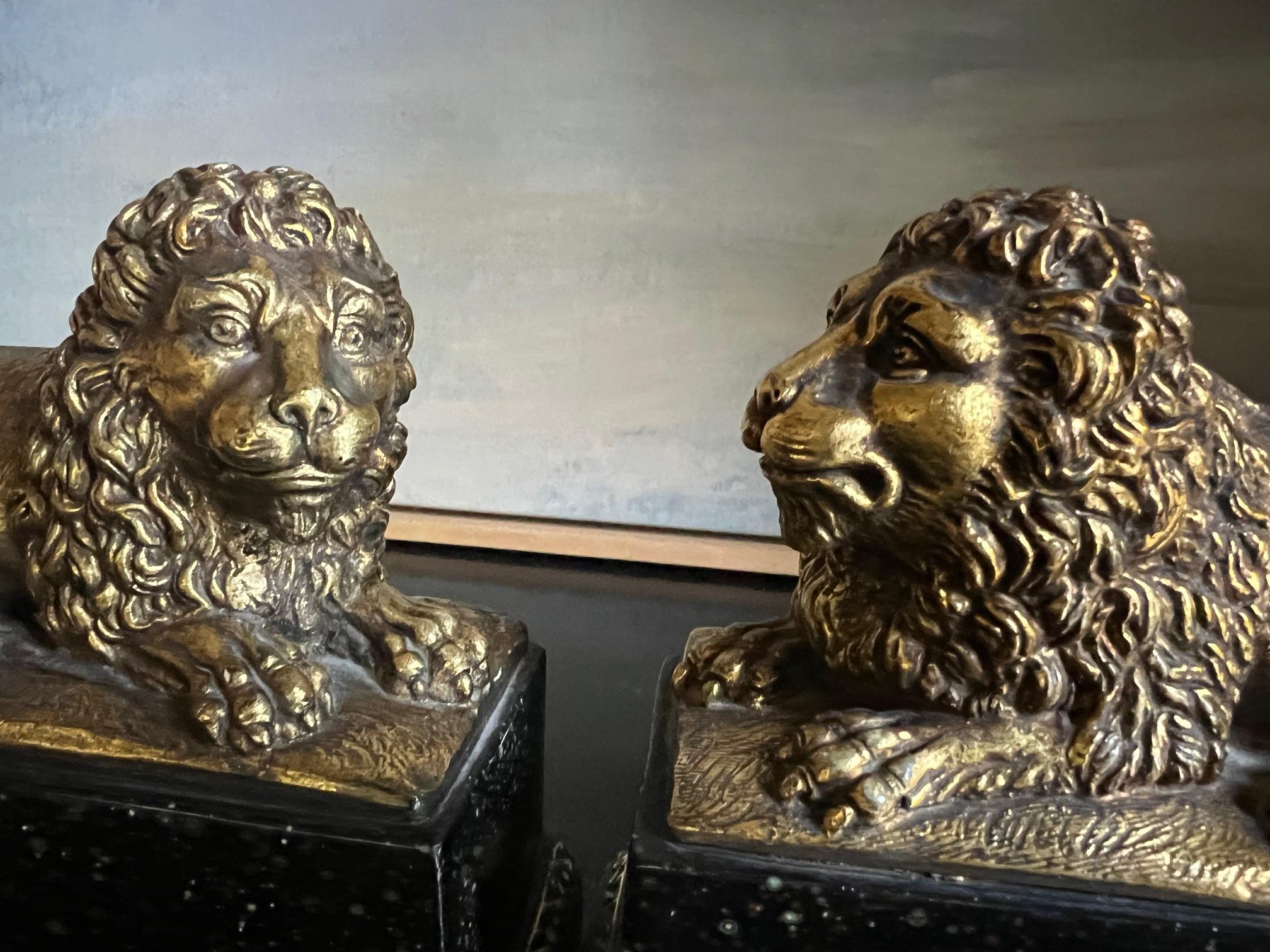 Lion bookends in a gold gilt finish on a faux black marble base by Borghese made in Italy in the 1960's. Made of cast plaster with a built in metal slide to go under the books.

Width of pedestal 3 inches, width of pedestal and metal plate 5.75