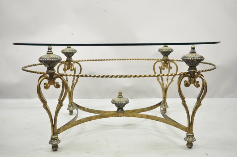 Vintage Italian Regency style wrought iron oval glass top urn finial coffee table. Item features oval glass top, distressed gold finish, urn form finials, wrought iron construction, very nice item, great style and form. Circa Late 20th Century.
