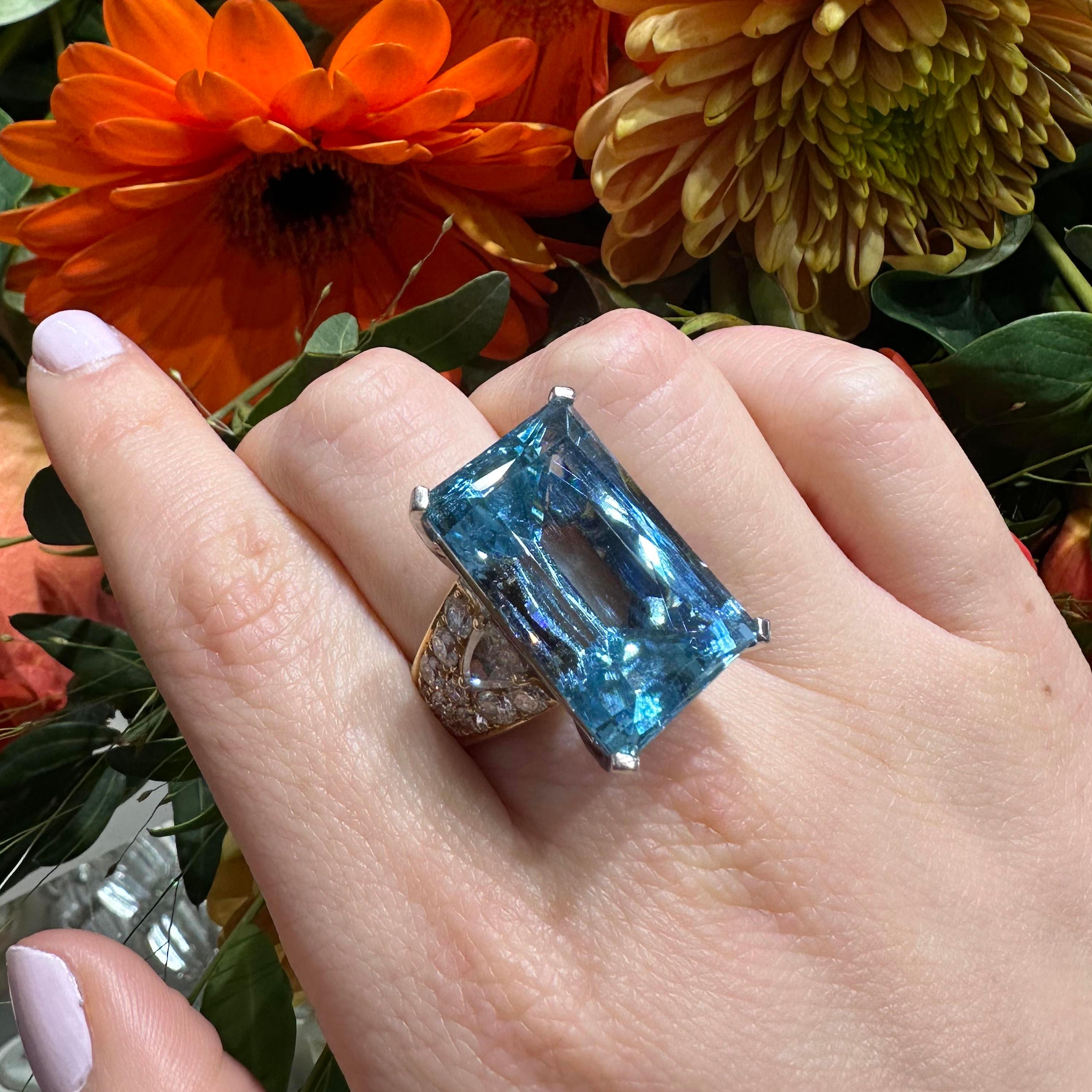 A vintage Italian Repossi aquamarine, diamond and gold dress ring, with a scissor-cut aquamarine, weighing approximately 35.00 carats, in a white gold four claw setting, with a trilliant-cut diamond set in the shoulders, surrounded by round