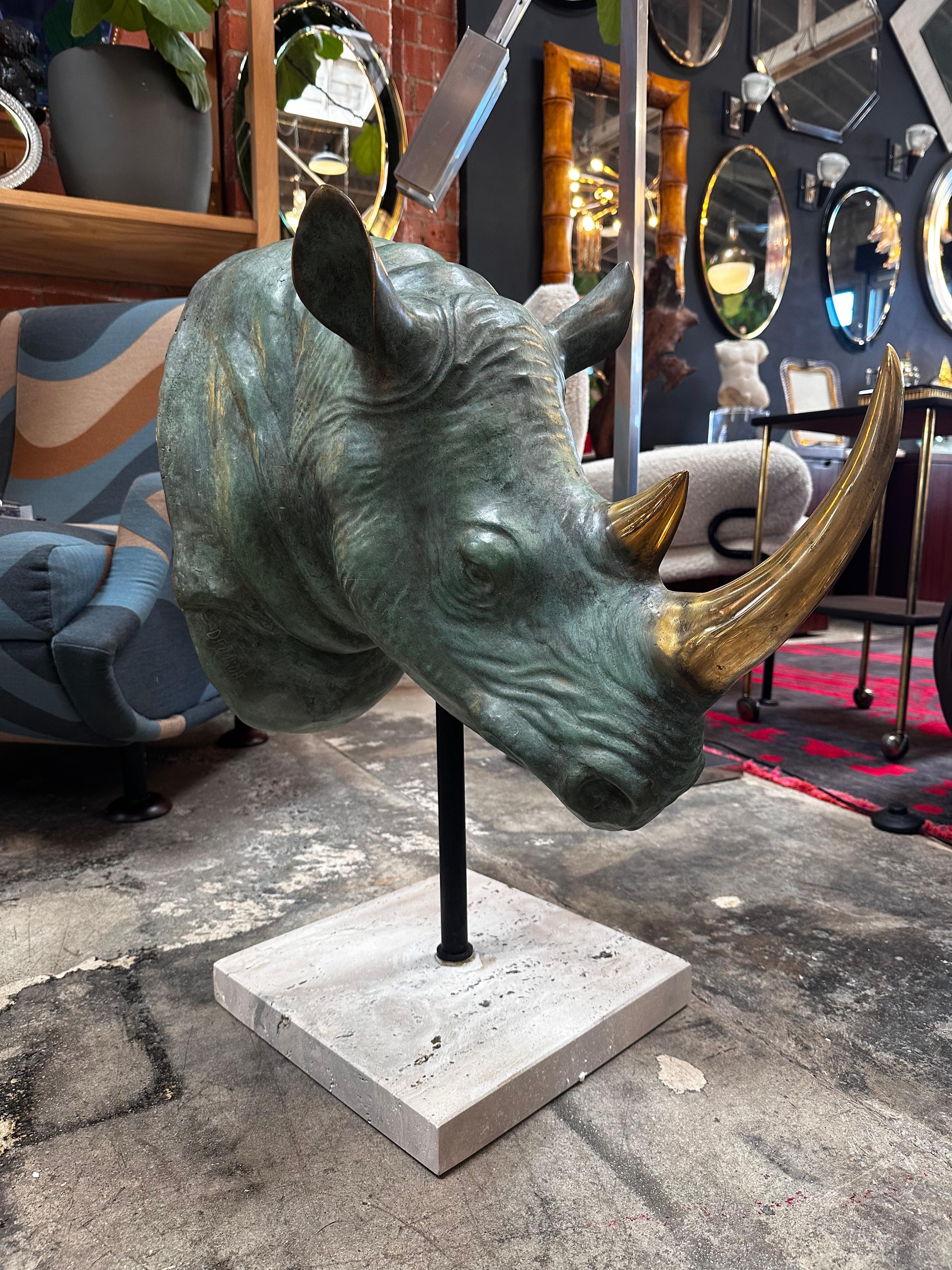 The Vintage Italian Rhino Bronze Sculpture from the 1970s is a striking piece showcasing a rhino head entirely crafted in bronze. It is elegantly presented on a square travertine base, capturing the essence of the 1970s with its unique blend of