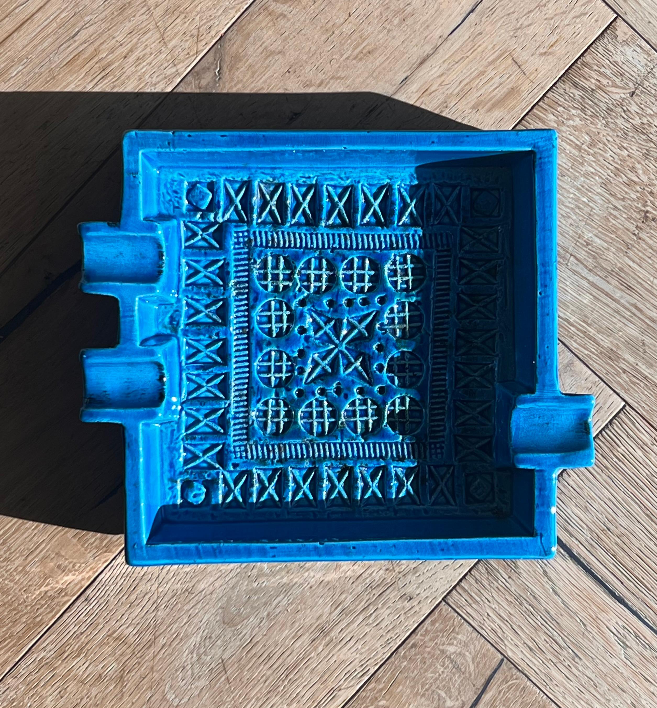 A vintage Italian mid century “Rimini Blu” ceramic ashtray by Aldo Londi for Bitossi, Italy 1960s. In vibrant cerulean blue and featuring an intricate hand-carved geometric motif on the base of the ashtray. One edge boasts two thick rivulets for a