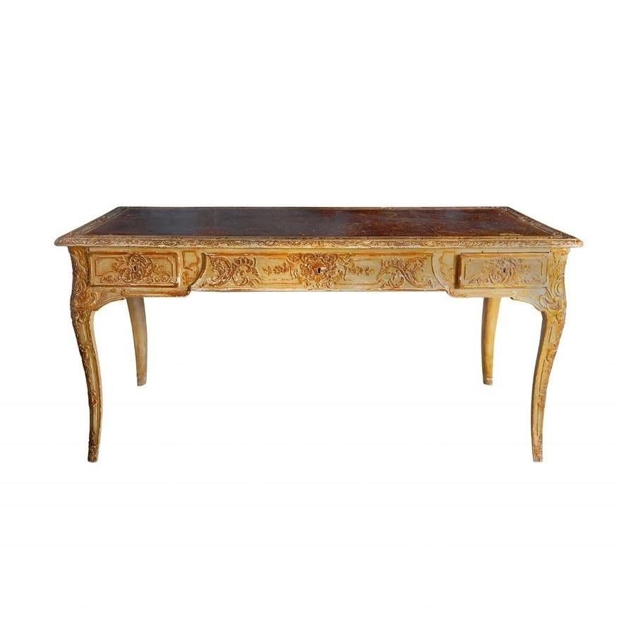Ein italienischer Vintage-Schreibtisch mit handgeschnitztem Massivholzrahmen im Rokoko-Revival-Stil, akzentuiert durch eine gewellte Schürze und eine vergoldete, geprägte Lederplatte. 

 