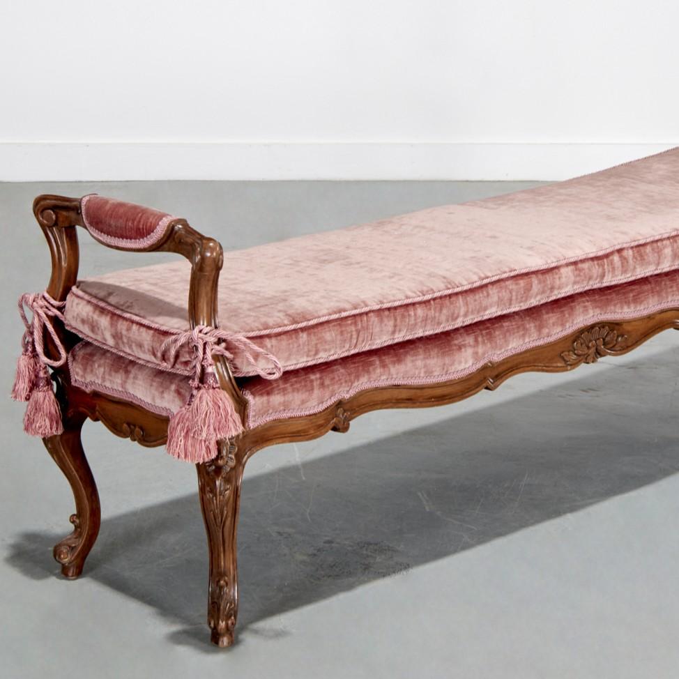 From The Collection of Plácido Domingo, an elegant Italian Rococo style walnut bench featuring cabriole legs, scrolling arms, and delicately carved floral motifs along the apron and knees. The frame has a warm, rich patina and retains its original