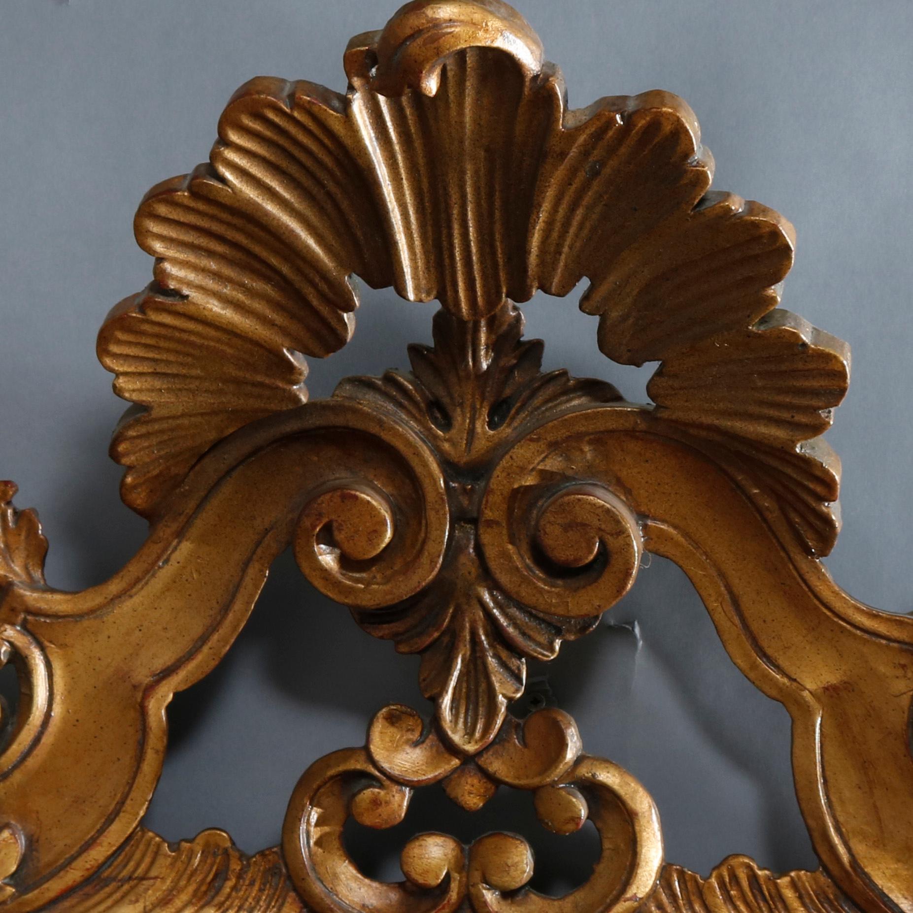 A vintage Italian Rococo style parclose over mantel wall mirror by Karges of Grand Rapids, MI offers giltwood frame with shell form cartouche flanked by scroll and foliate elements, 20th century

Measures: 62