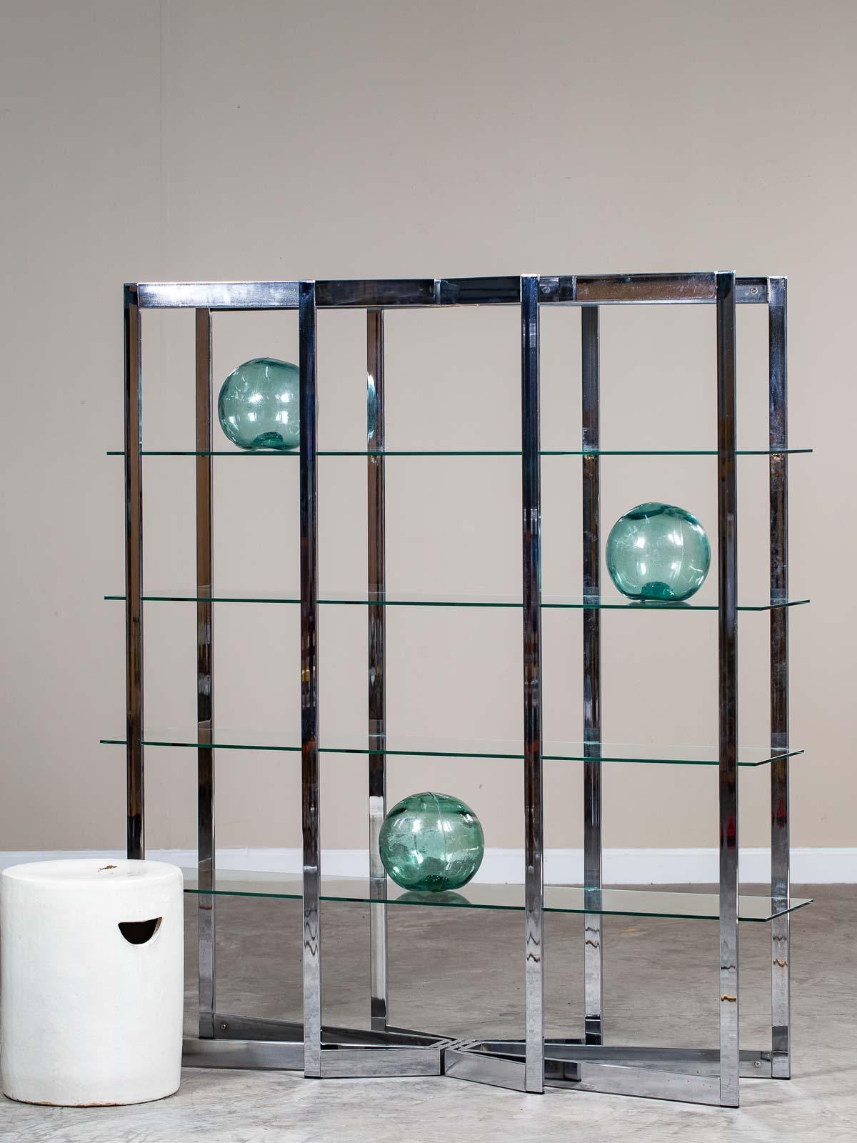 This striking vintage Italian chrome etagere bookcase, designed by Romeo Rega, with glass shelves circa 1975 has a unique profile. With four separate chromed metal elements creating the supports please look at the diagonal join at the top and base.