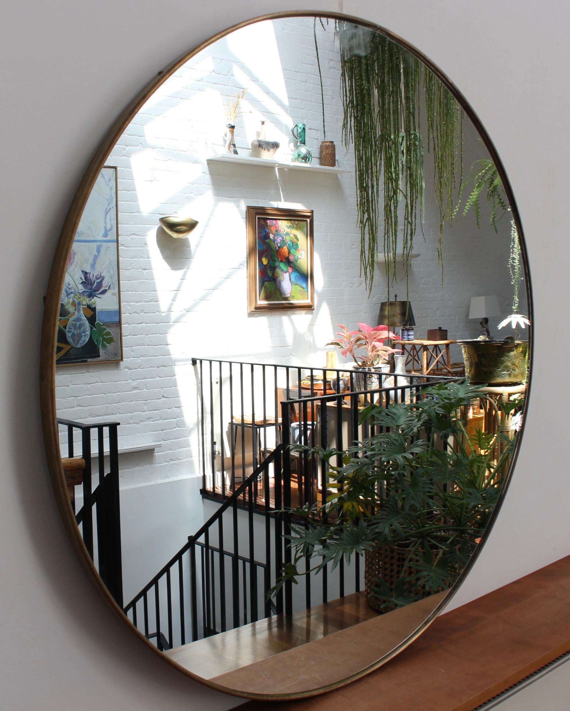 Mid-century Italian wall mirror with brass frame (circa 1960s). The mirror is a perfectly shaped circle in a Modern style. It is in good overall condition with just a light blemish on the glass. A beautiful, aged patina develops on the brass frame.