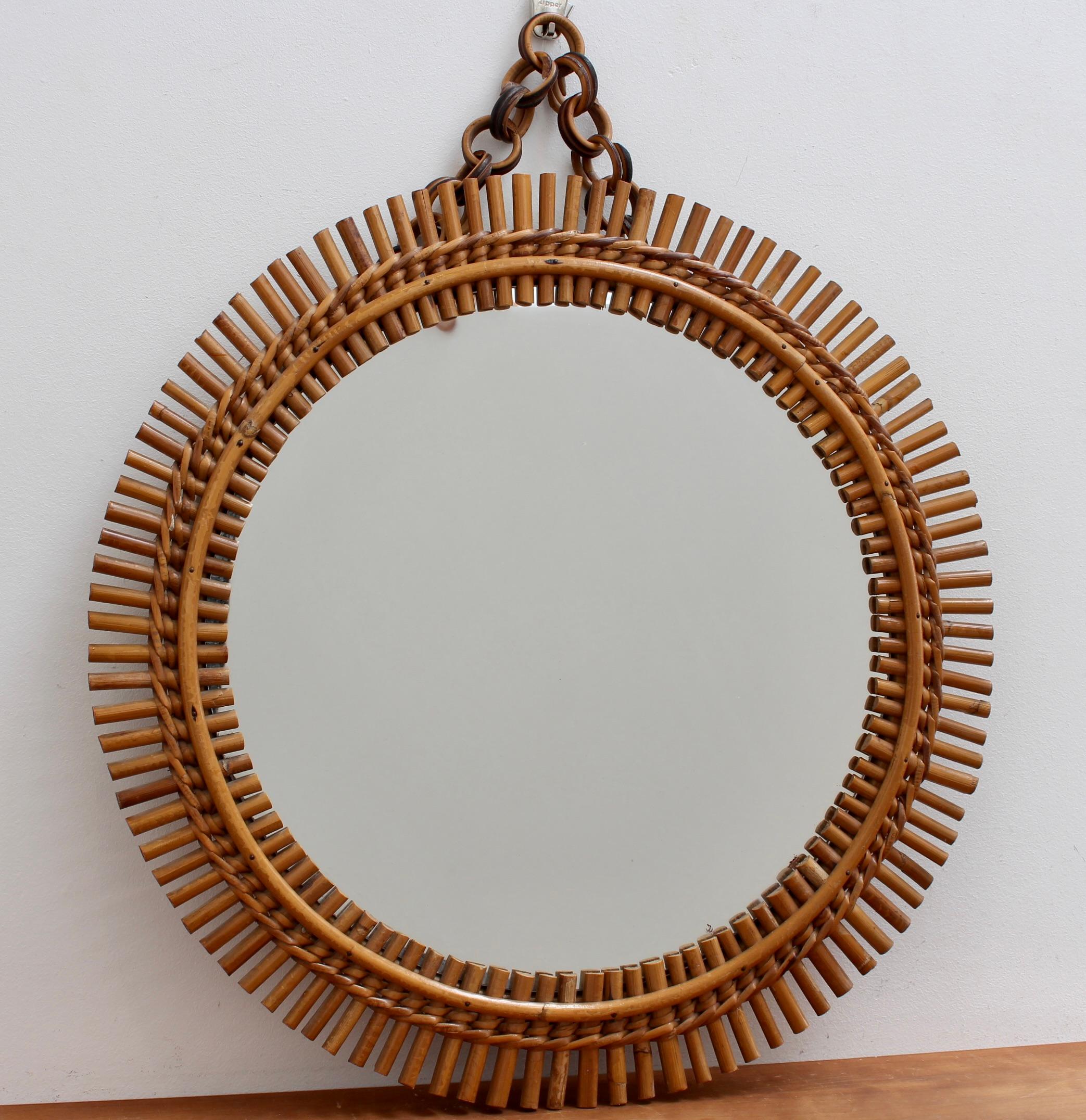 Italian vintage rattan round wall mirror with hanging chain (circa 1960s). This mirror has a very delightful shape bound together with rattan rope weave motif. The rattan hanging chain is intact and adds to its appeal. There is a characterful, aged
