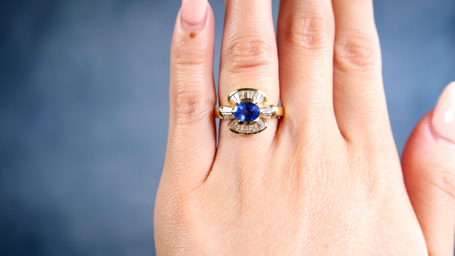 One Vintage Italian Sapphire Diamond 18k Yellow Gold Ring. Featuring one oval mixed cut sapphire weighing approximately 1.00 carat. Accented by 22 tapered baguette cut diamonds with a total weight of approximately 1.10 carats, graded F-G color, VS