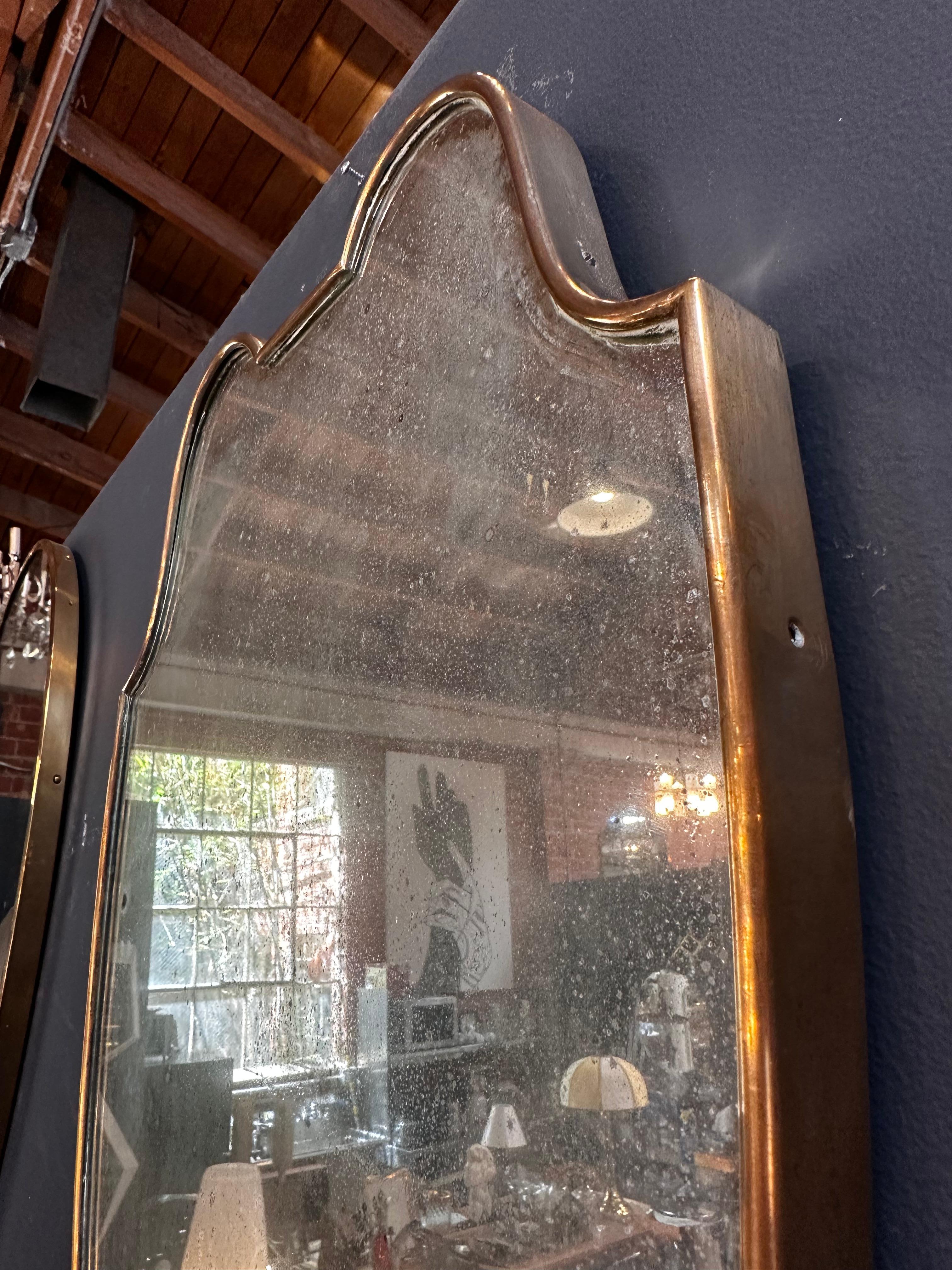 A vintage 1960s Italian brass wall mirror, showcasing original patina and an exceptionally chic brass frame. This piece combines timeless style with a touch of authentic character, embodying the essence of sophisticated design from that era.

