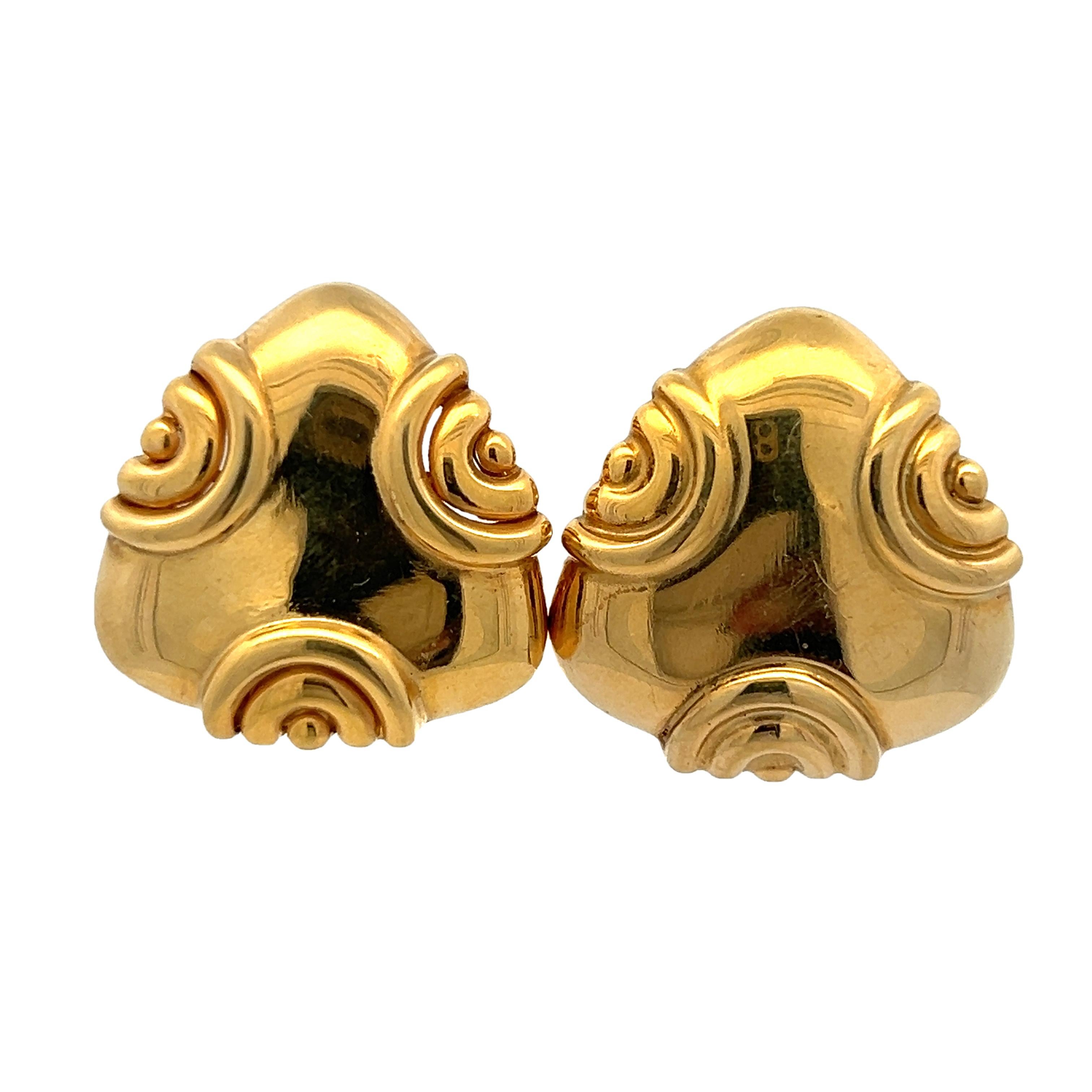 A beautiful pair of vintage Italian earrings crafted in richly polished 18K yellow gold, showcasing a bold sculptural silhouette with swirling relief motifs. These triangular clip-on earrings are emblematic of timeless Italian design—elegant,