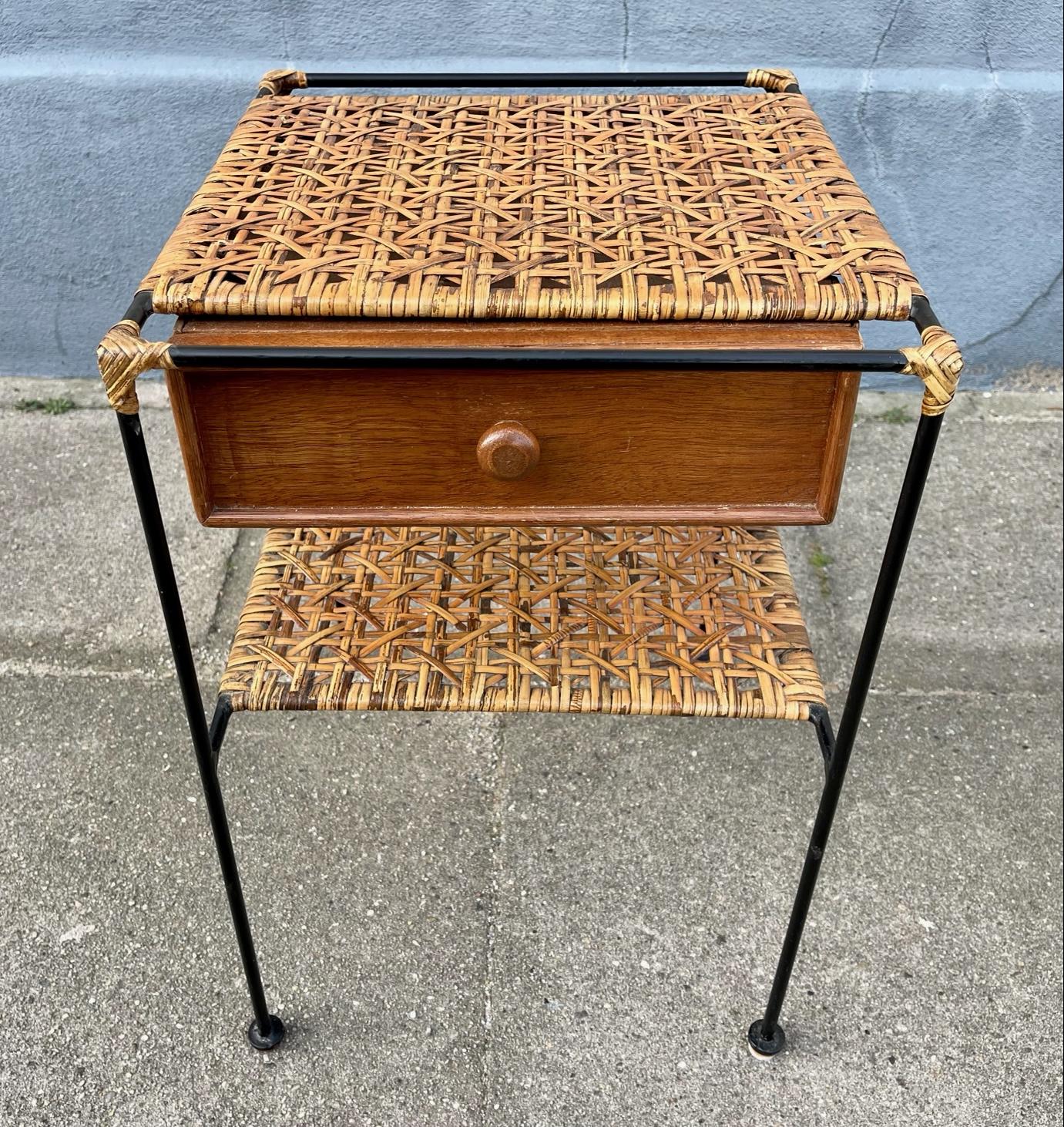 A Carl Auböck inspired small side, shaker or entry hall table made from tubular black painted solid steel, woven rattan table top a magazine shelf and featuring a practical single drawer in teak. Its was made in Italy during the 1960s and the rattan