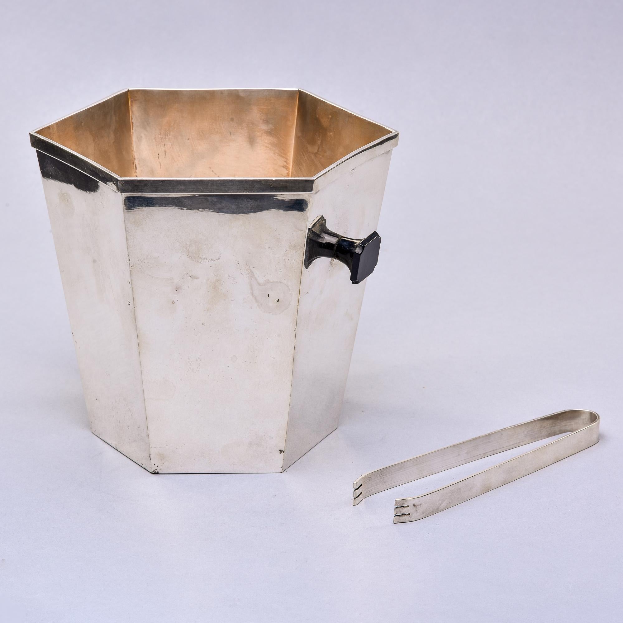 Found in Italy, this circa 1970s ice bucket and matching tongs are silver plated. Bucket is six-sided and just under 8” tall. Unknown maker but marked on underside of base. Sold and priced as a set with bucket and tongs. 

Very good overall