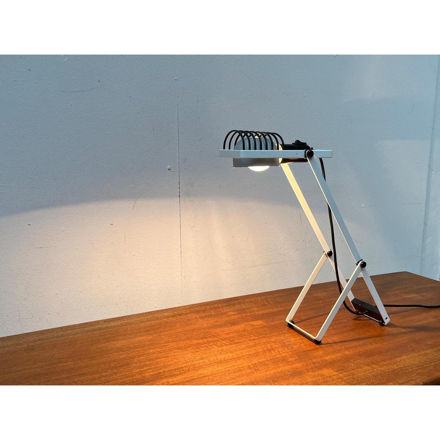 Rare table lamp from the Sintesi series by the Italian manufacturer Artemide and designed by Ernesto Gismondi.

The lamp has the characteristic elements of the Sintesi series, the black struts, the white frame with joint, the aluminum reflector. The