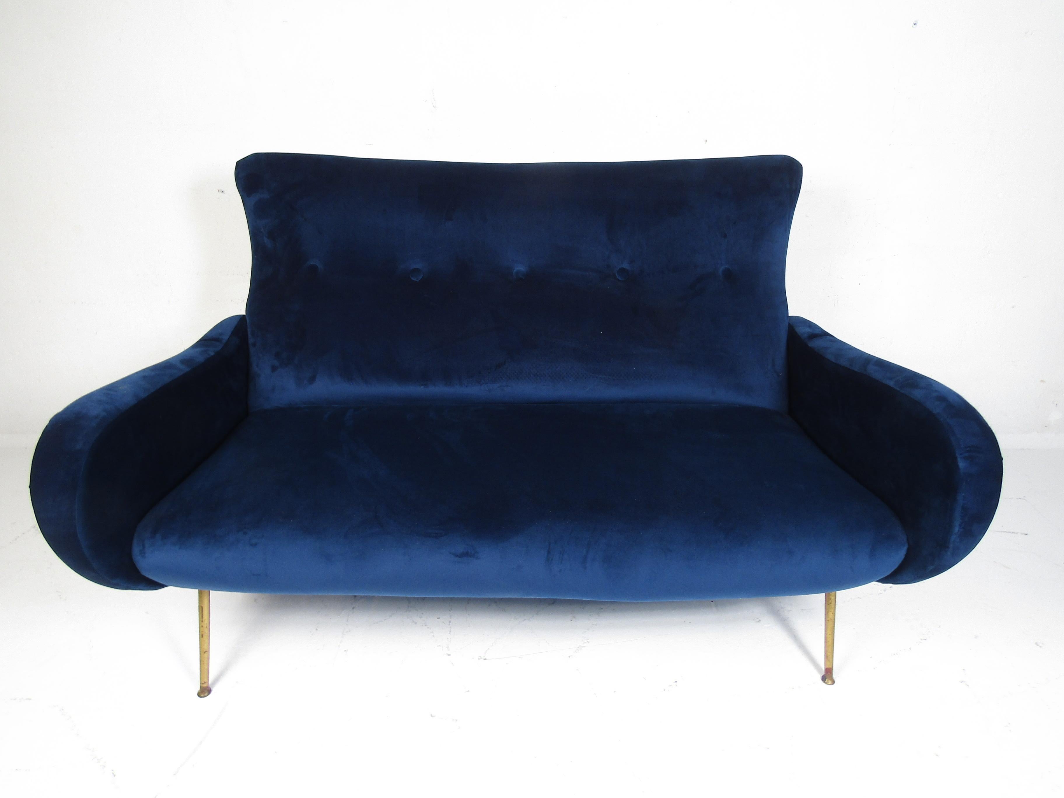 Stylish Italian sofa. Deep blue velvet upholstery with tufted backrest. Sculpted arms. Splayed brass legs. Please confirm item location with dealer (NJ or NY).