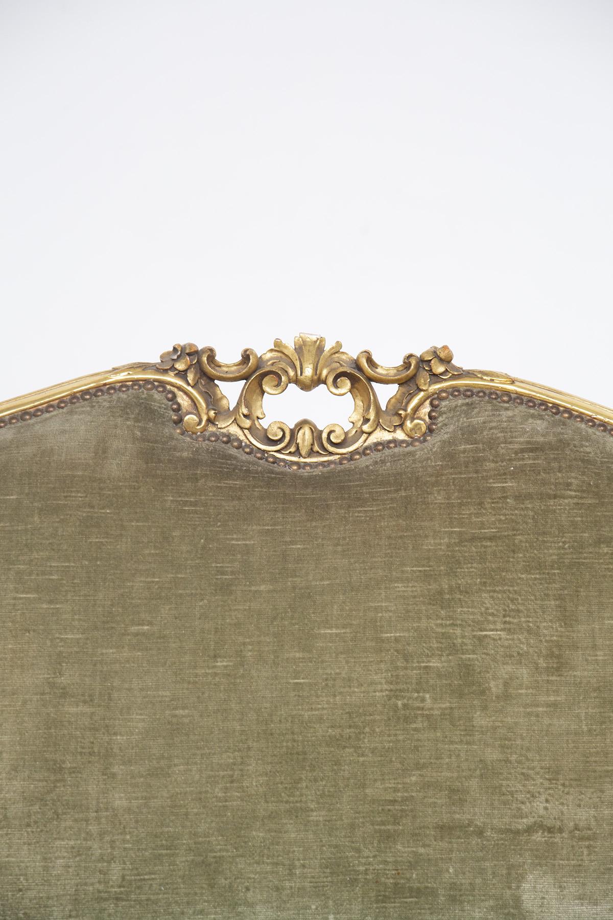 Le canapé vintage est de style Louis XVI et a été fabriqué en Italie au début des années 1900. Le grand canapé à trois places est recouvert du magnifique velours vert d'origine. Le bois doré est décoré de motifs et de détails typiques de ce style.