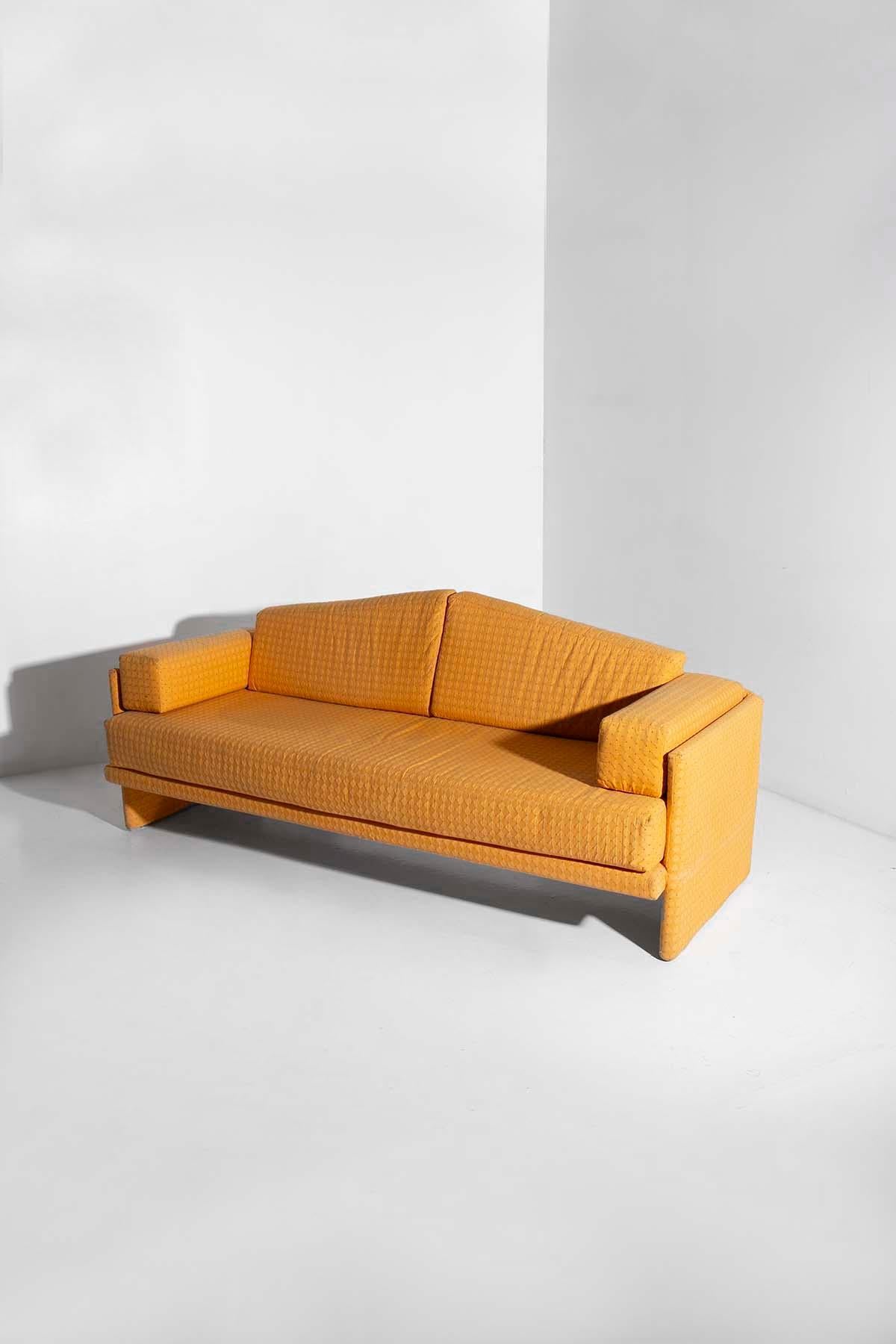 A journey back in time, straight to the dawn of innovation and creativity of the 1980s, this Italian vintage sofa is a celebration of the design that revolutionized contemporary furniture. Upholstered in a yellow quilted fabric, adorned with